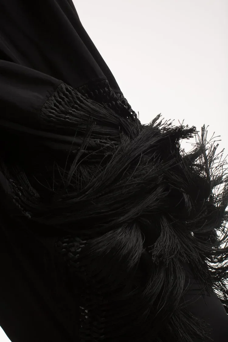 Victorian fringe cape, Material & Fringe Detail
Close-up of black textile featuring dense fringe construction, braided detailing and expressive surface movement.
Surface finish becomes the defining characteristic, creating texture through layered fib
