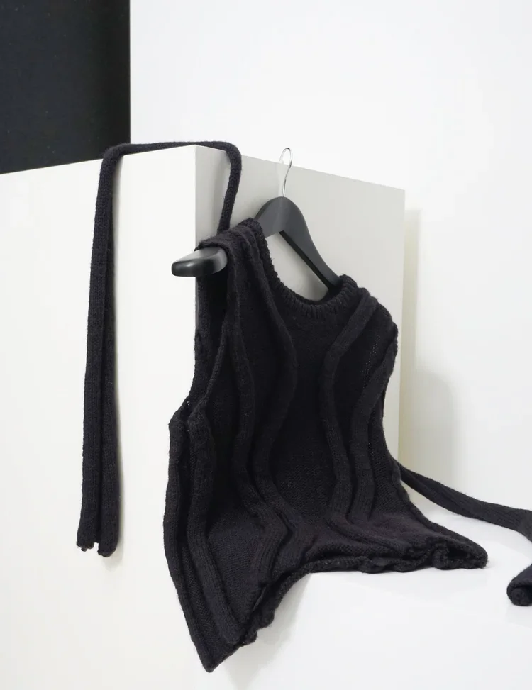 Sculptural Knit Engineering
Black knitted garment incorporating tubular forms and engineered rib structures, demonstrating three-dimensional knit construction and experimental silhouette.
The garment grows from the knit itself, where structure is cre