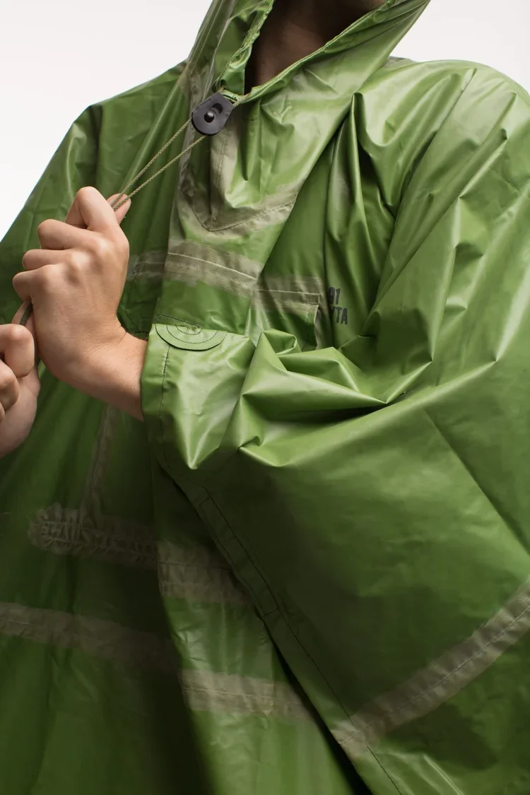 Technical Utility Outerwear. Rubberised green military poncho
Protective technical outerwear in coated green fabric examining waterproof construction, taped seams and functional fastening systems.
Utility garments continue to influence contemporary a