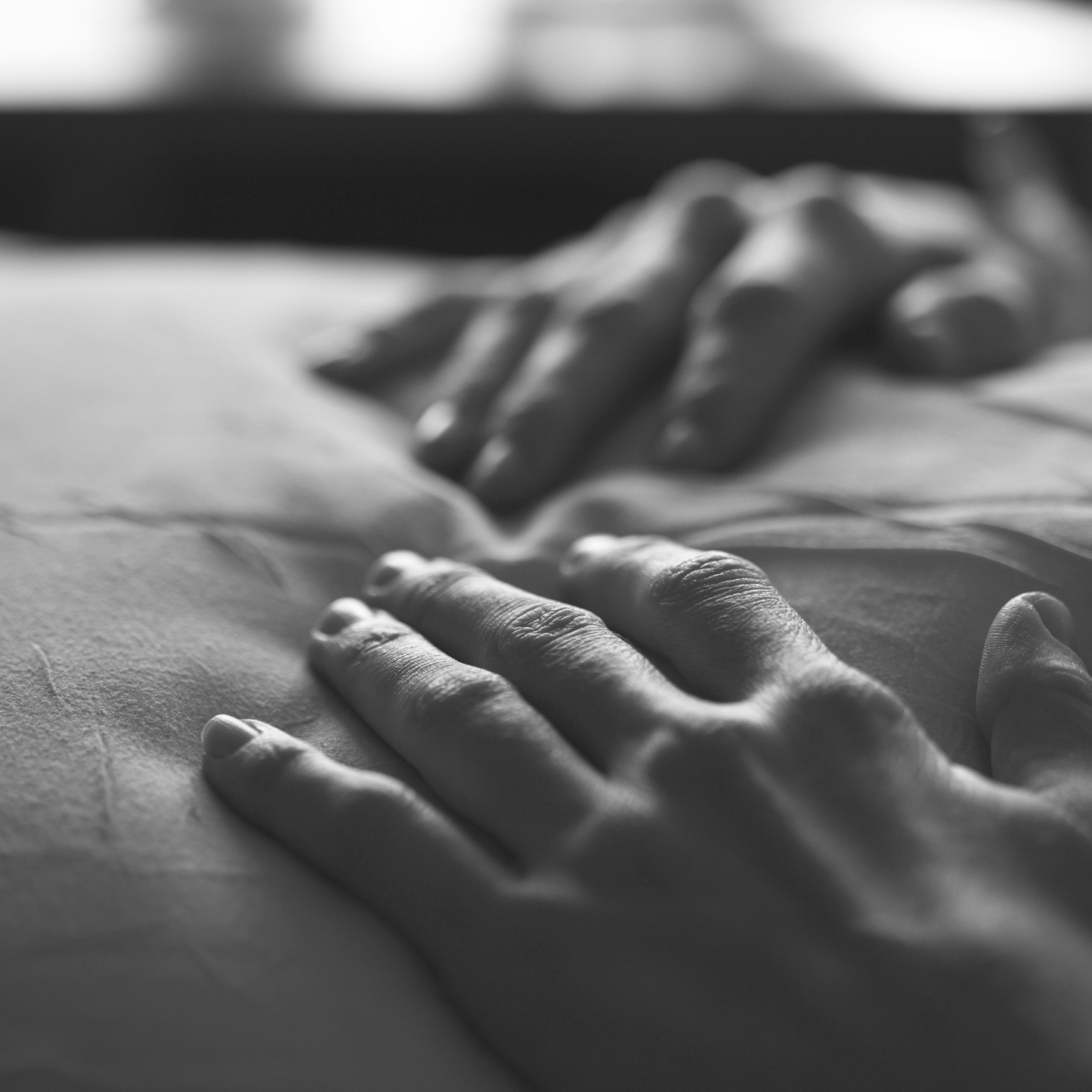 Close-up of hands resting on a person's chest or stomach, black and white photo.