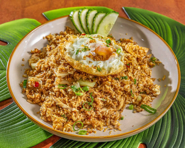 A bowl of fried rice garnished with sliced cucumber, lime, and topped with a fried egg and chopped green onions. Kaia's Kitchen Harristown