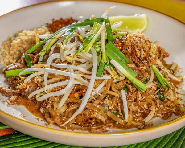 Plate of Pad Thai with bean sprouts, green onions, crushed peanuts, lime wedge, and chili flakes. Kaia's Kitchen Harristown