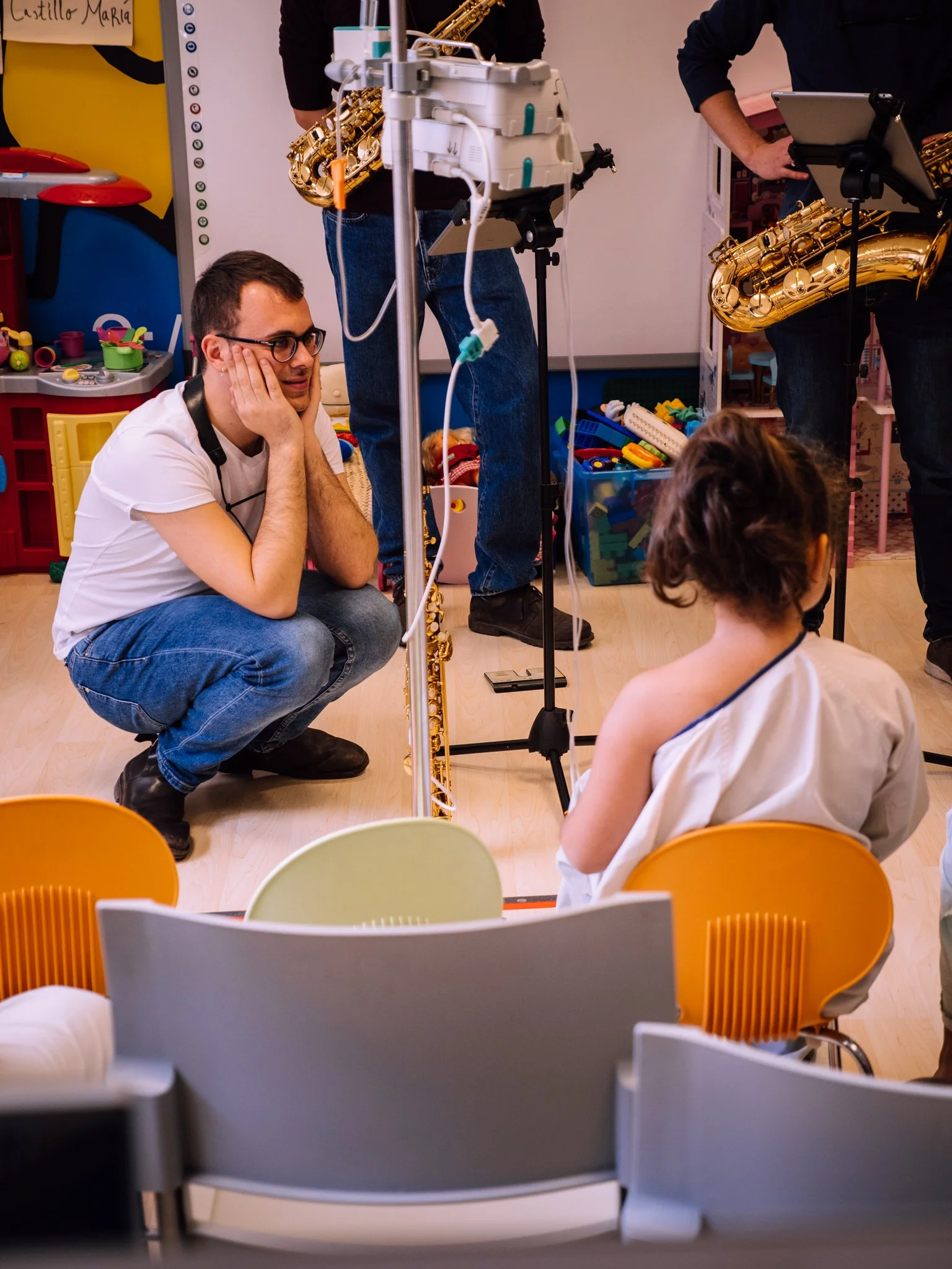 Un grupo de músicos tocando en una sala de juegos, con niños observando, en un ambiente colorido y alegre.