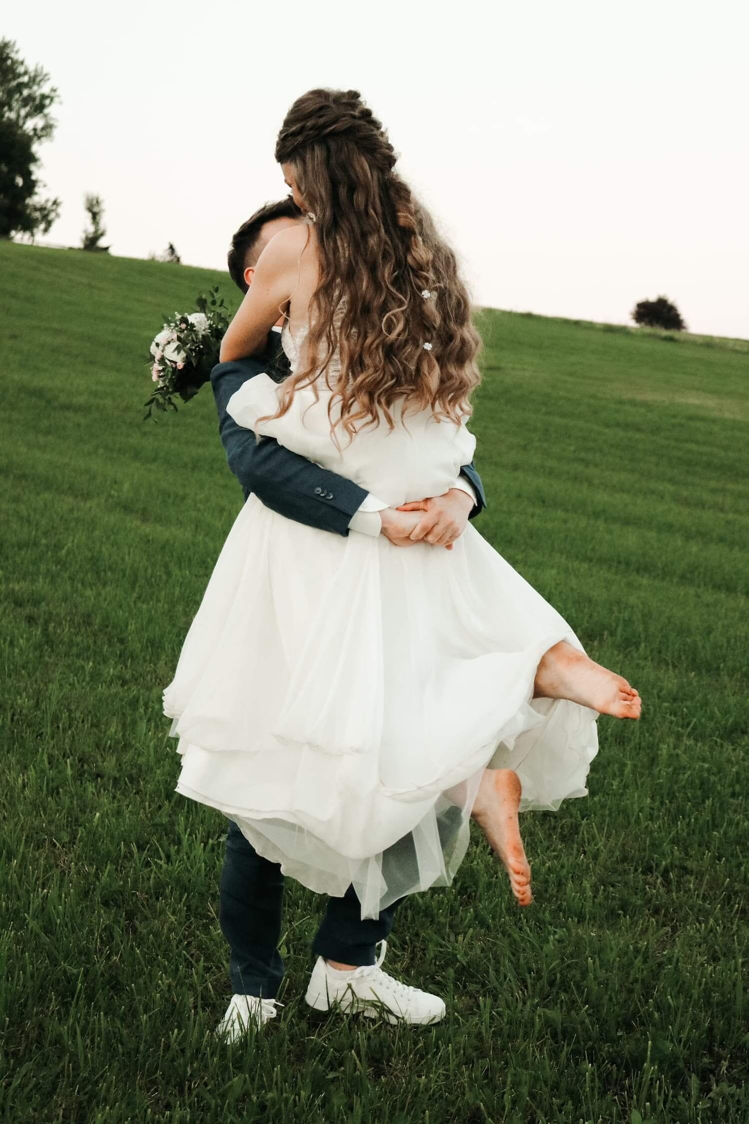 Bräutigam hebt seine Braut lachend auf einer Wiese in Biberach an der Riß hoch – emotionales Hochzeitsfoto.