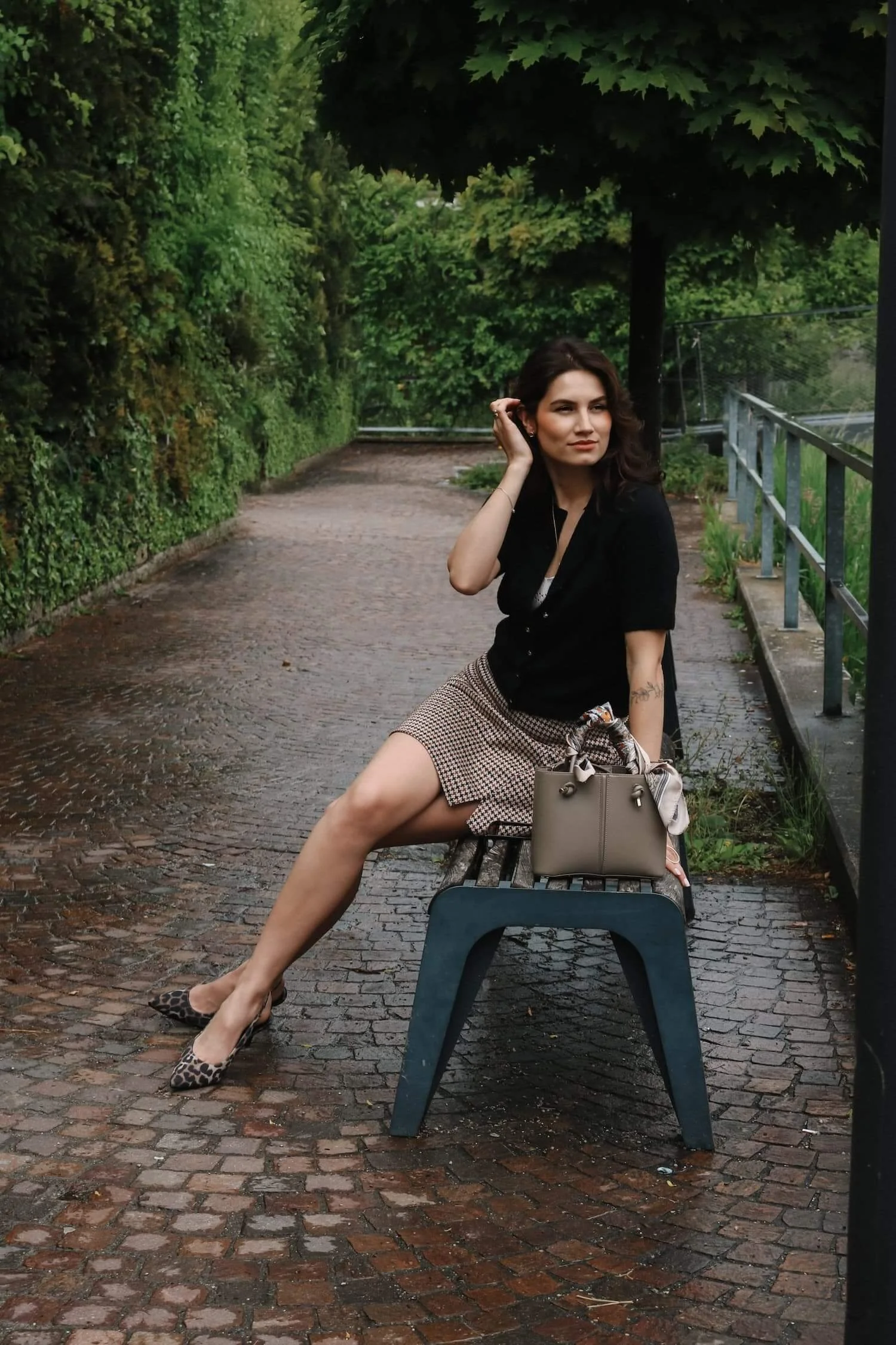 Elegantes Streetstyle-Portrait einer Frau auf einer nassen Pflasterstraße in Memmingen.