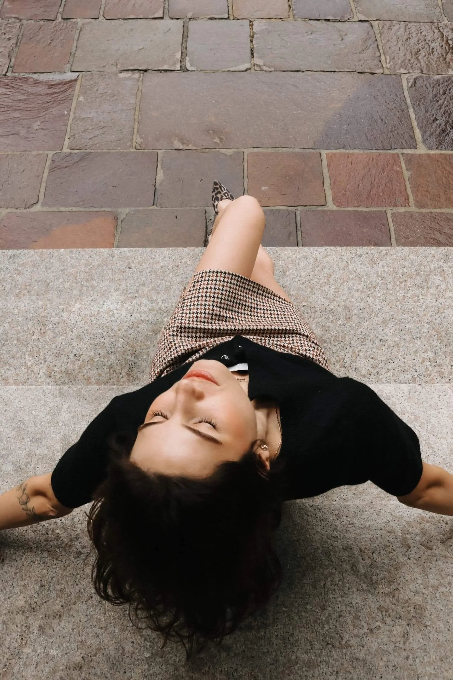 Künstlerisches Editorial-Portrait einer Frau, die entspannt auf Steinstufen in Biberach liegt.