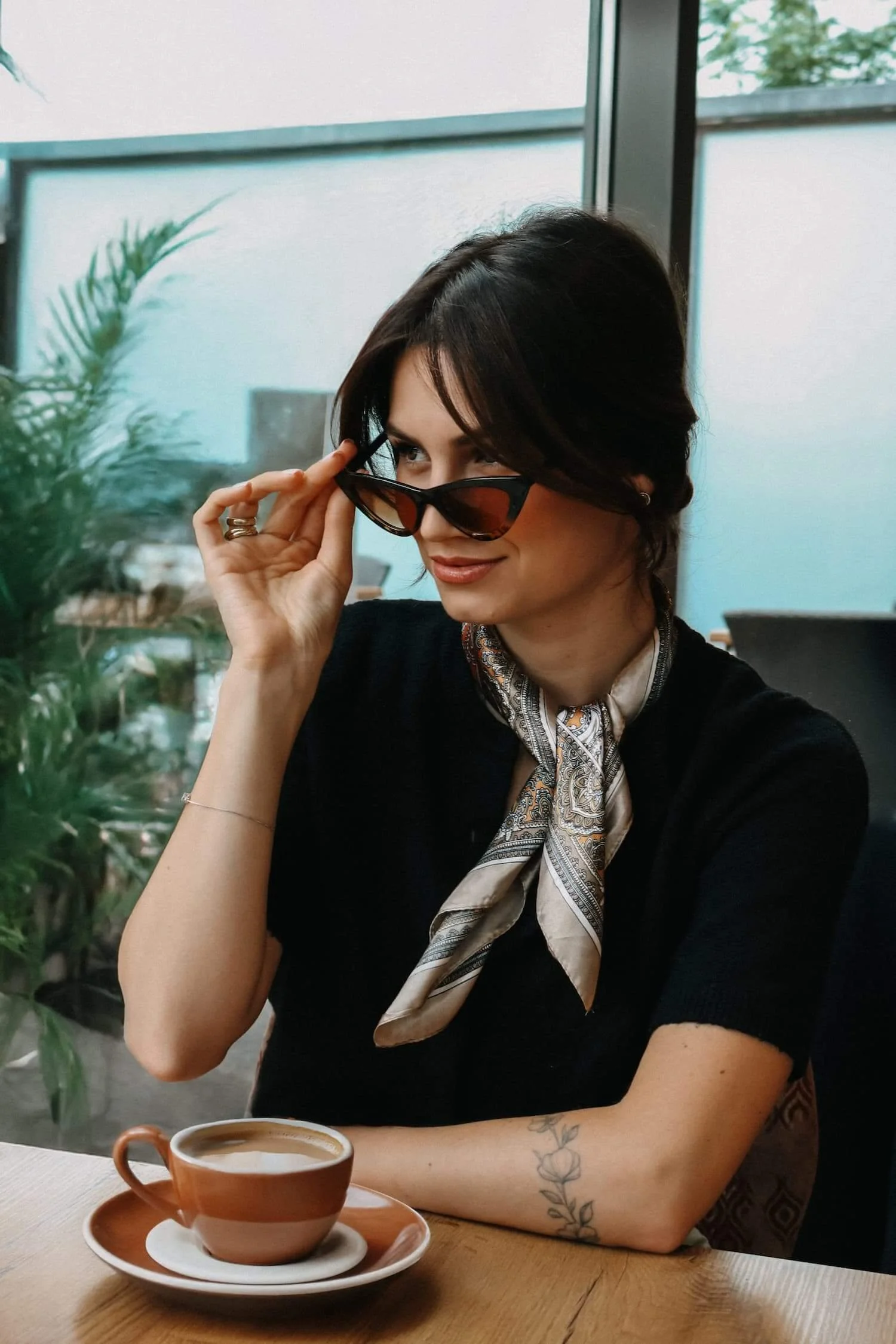 Modernes Portrait einer Frau mit Sonnenbrille und Kaffee im Café in Biberach.
