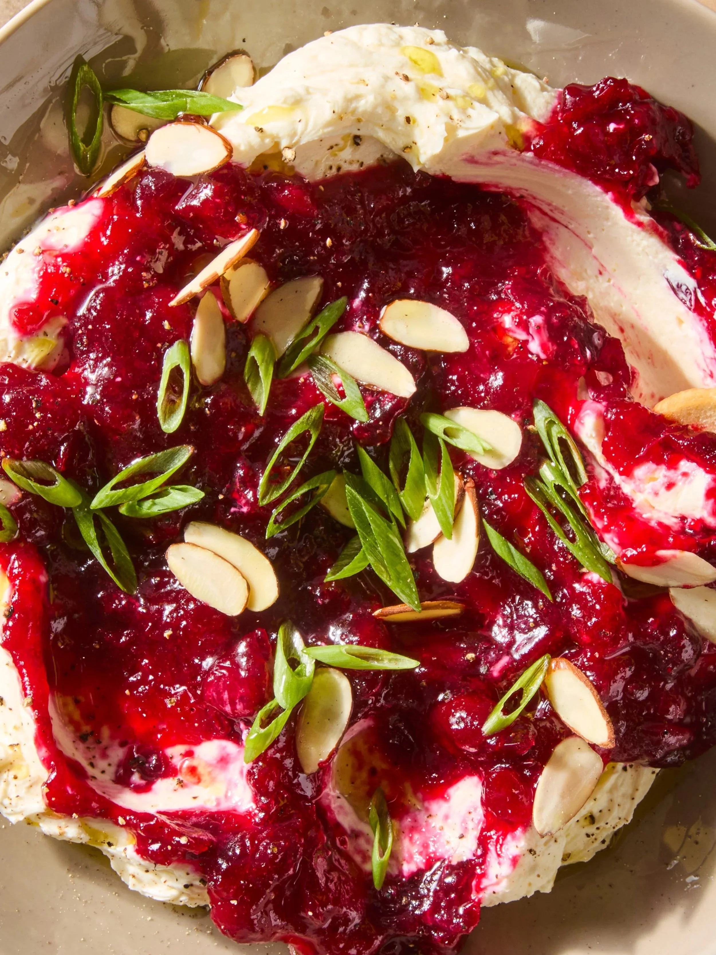 Dessert with whipped cream, raspberry sauce, sliced almonds, and chopped green almonds.