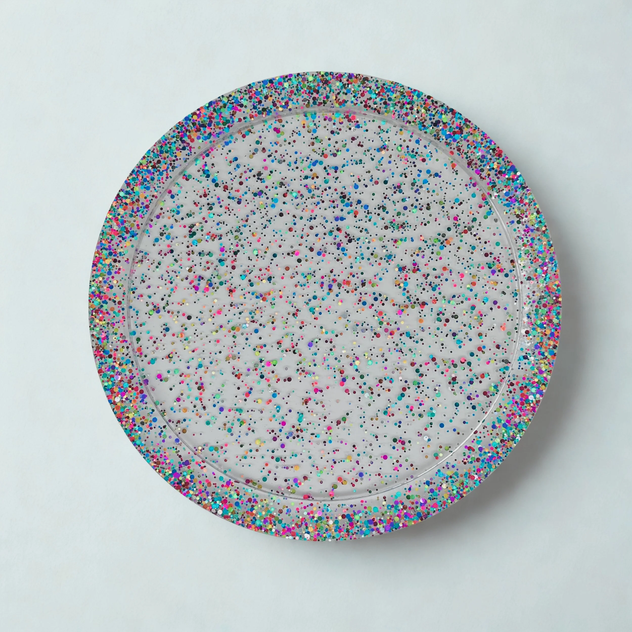 Clear circular tray filled with multicolored confetti, with glittery borders on the rim.