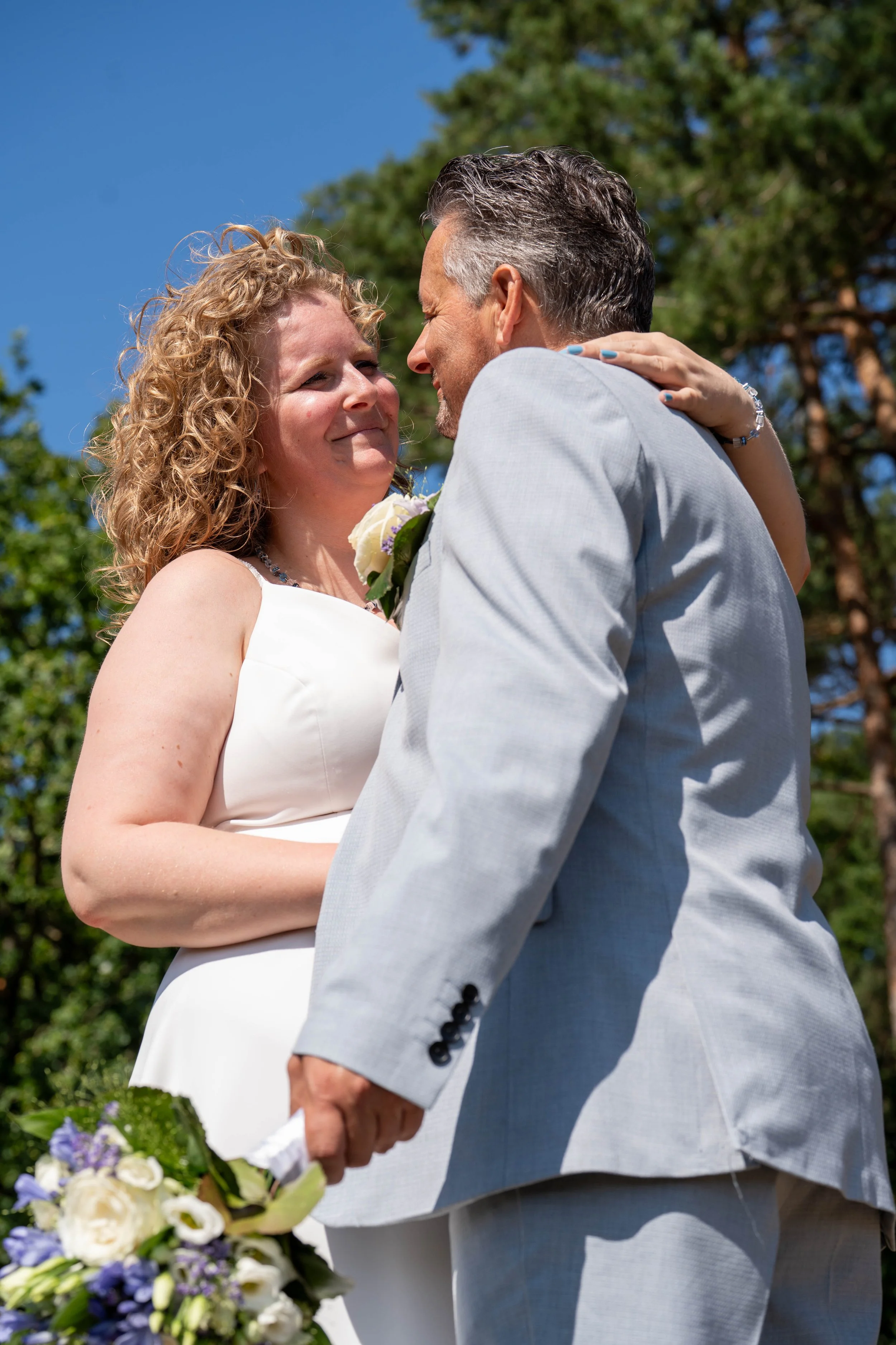 Trouwfotografie van een bruidspaar tijdens een romantisch moment in de buitenlucht.