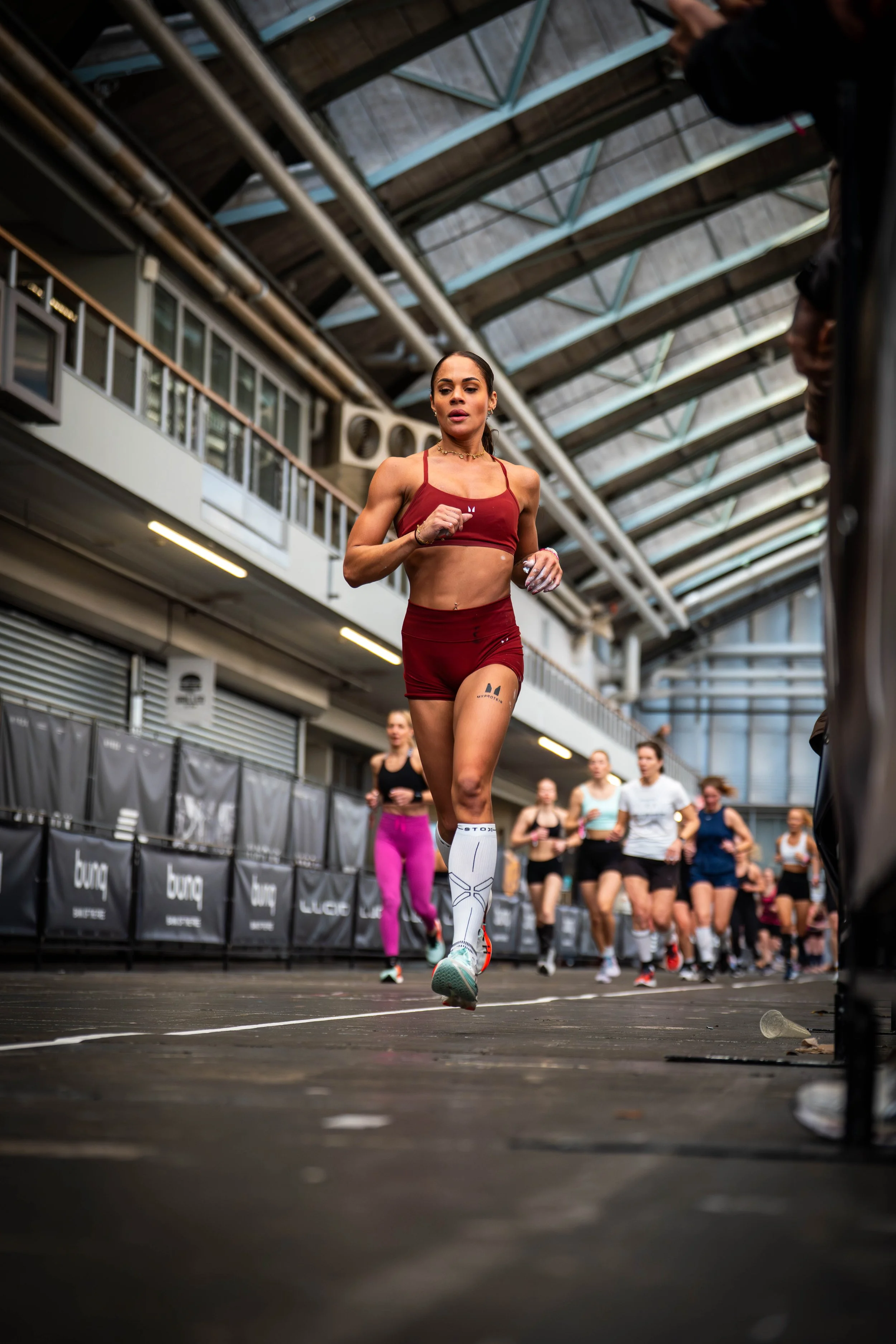 HYROX fotografie van een atleet tijdens het hardlopen in een indoor wedstrijdomgeving.
