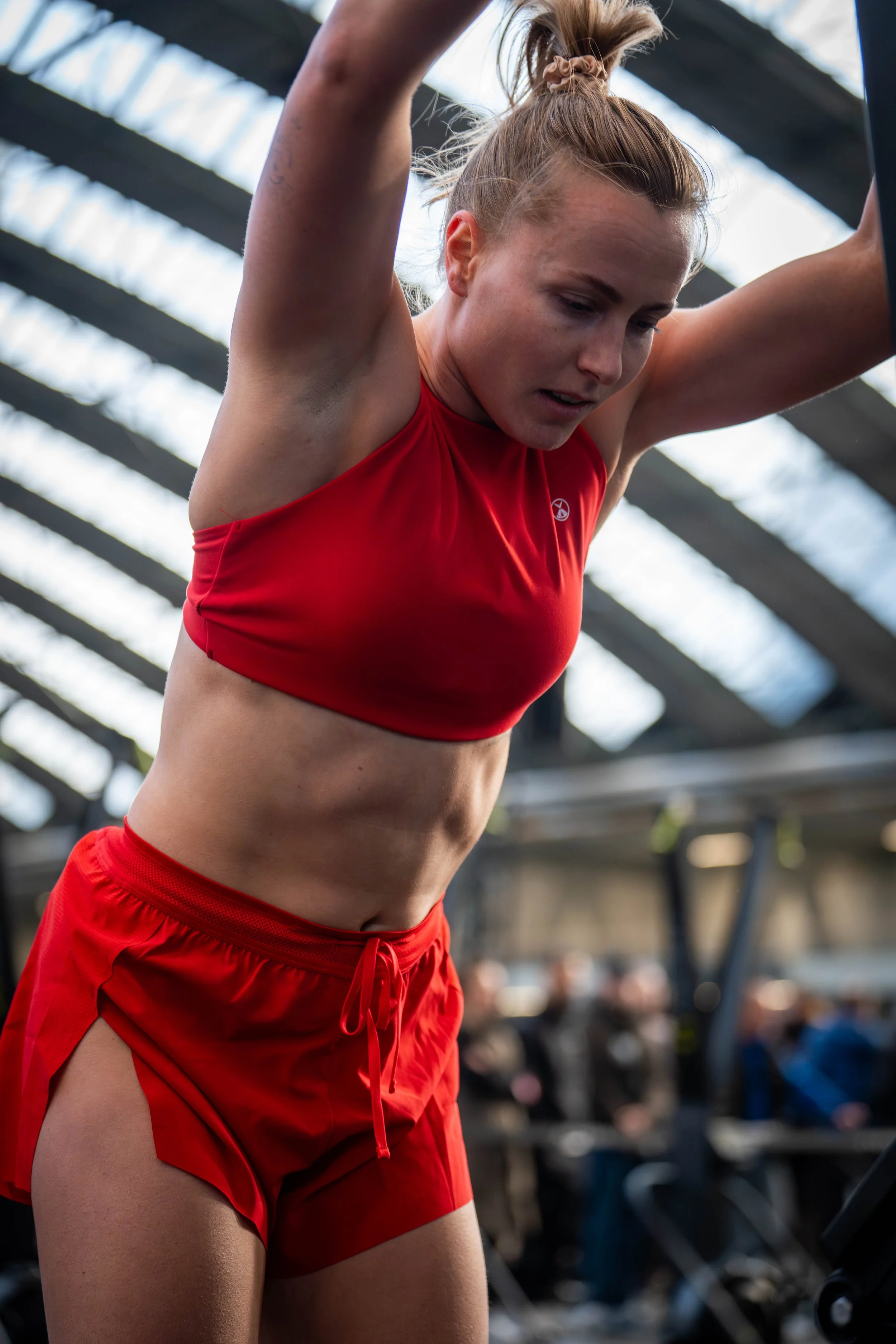 Close-up of a woman in red athletic wear exercising in a gym or sports facility.