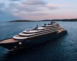 A large luxury yacht sailing on the water during sunset or twilight.