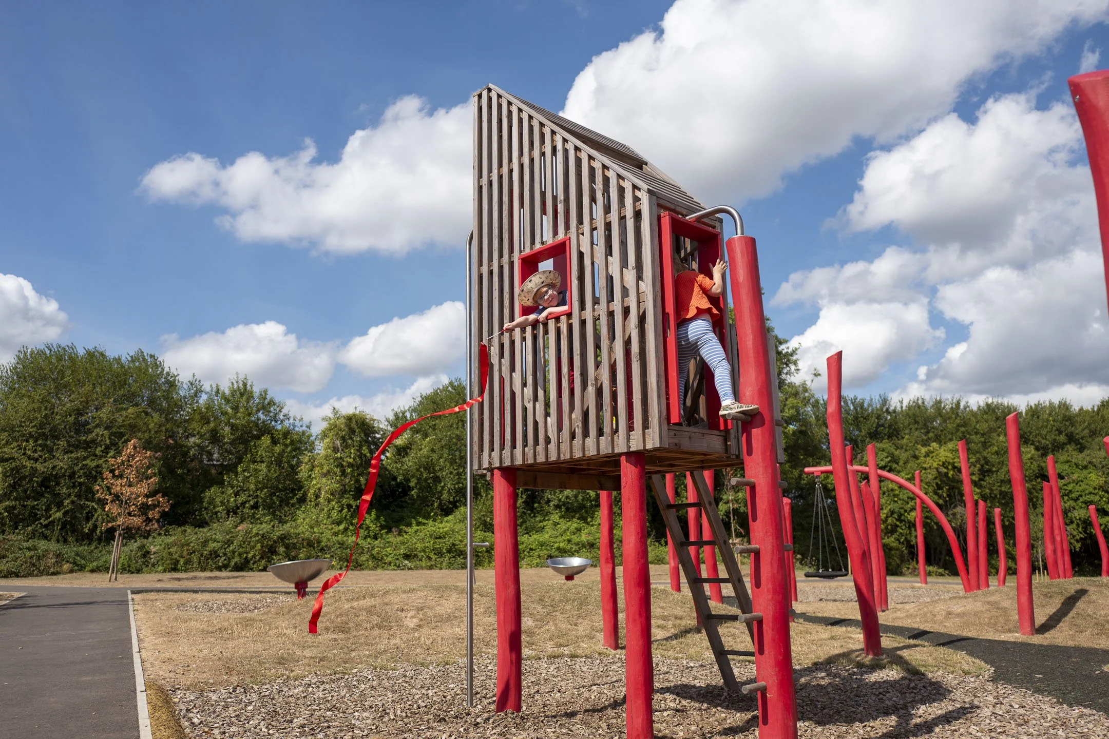 A drawing of a red wooden playhouse on stilts with a ladder on the right side and a white slide on the left side, set against a background of vertical pink and red stripes.