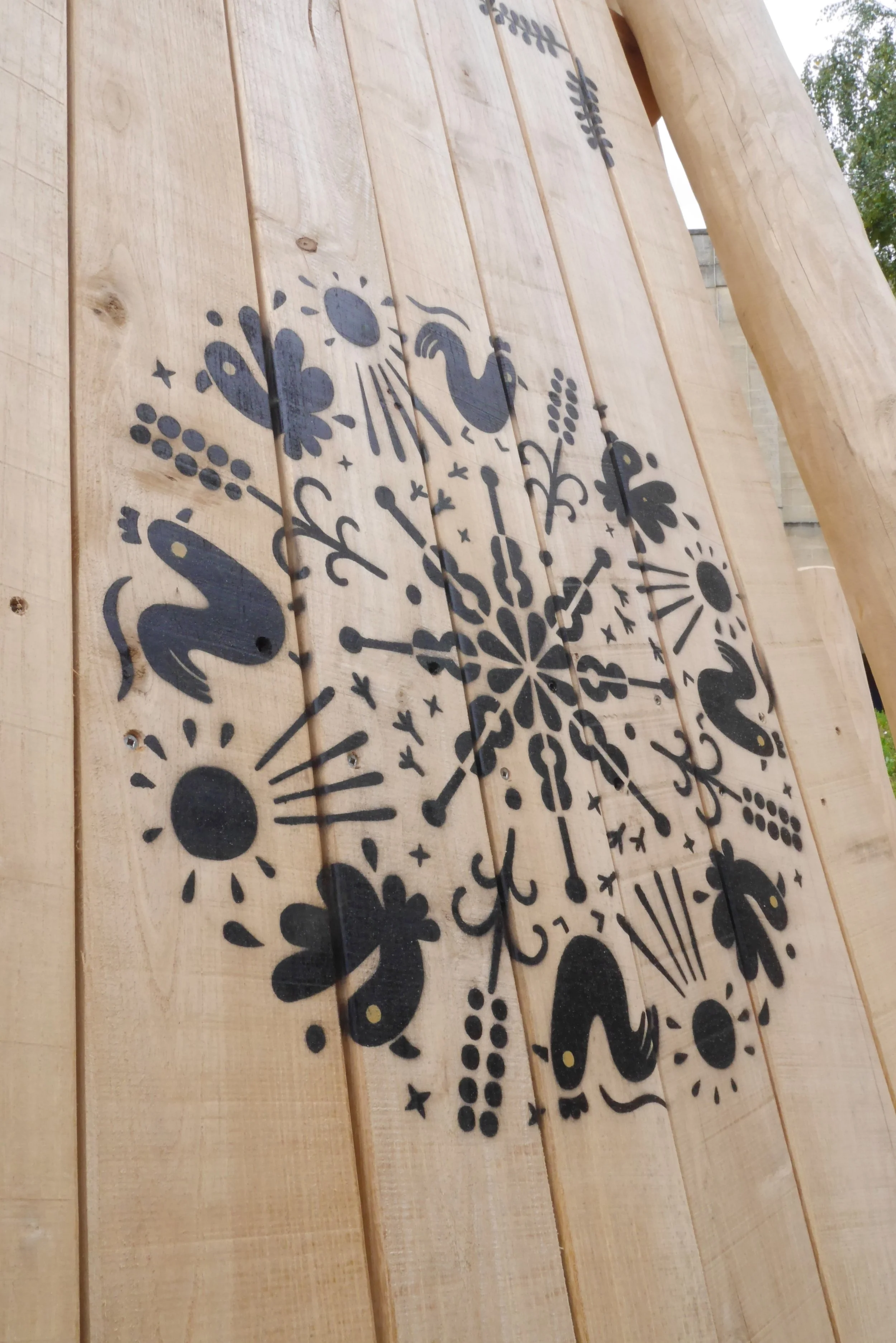 Decorative black floral and animal illustrations forming a circular pattern on wooden planks.