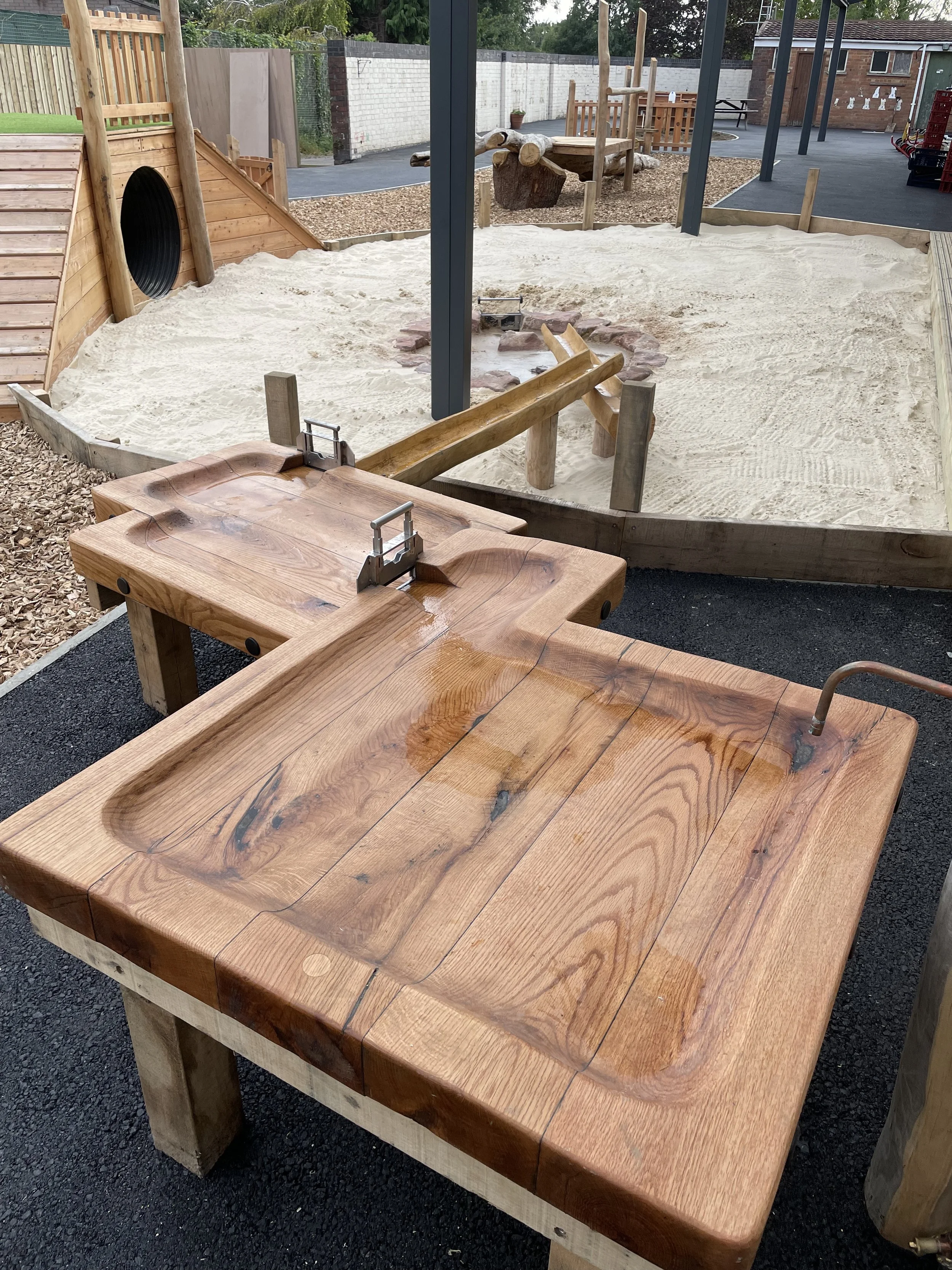 Wooden outdoor play area with sandpit and climbing structures for children.