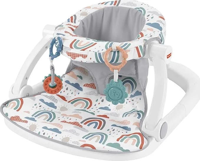 Baby bouncer chair with rainbow, cloud, and sun pattern, with attached colorful toys.