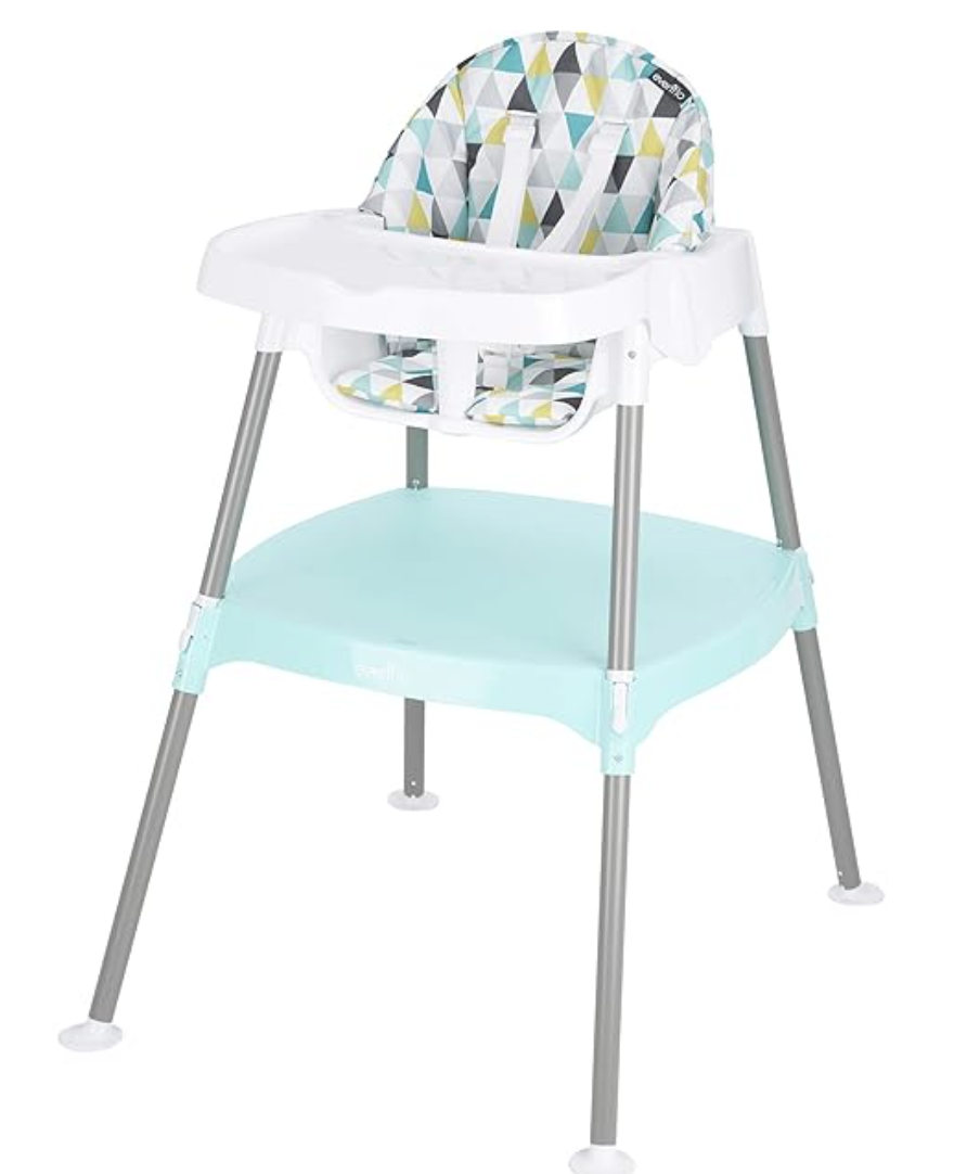 A baby high chair with a geometric pattern on the cushion, white tray, and metal legs with a lower storage shelf.