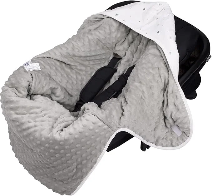 A baby car seat with a light gray, plush, dotted blanket cover and a white hood with star patterns.