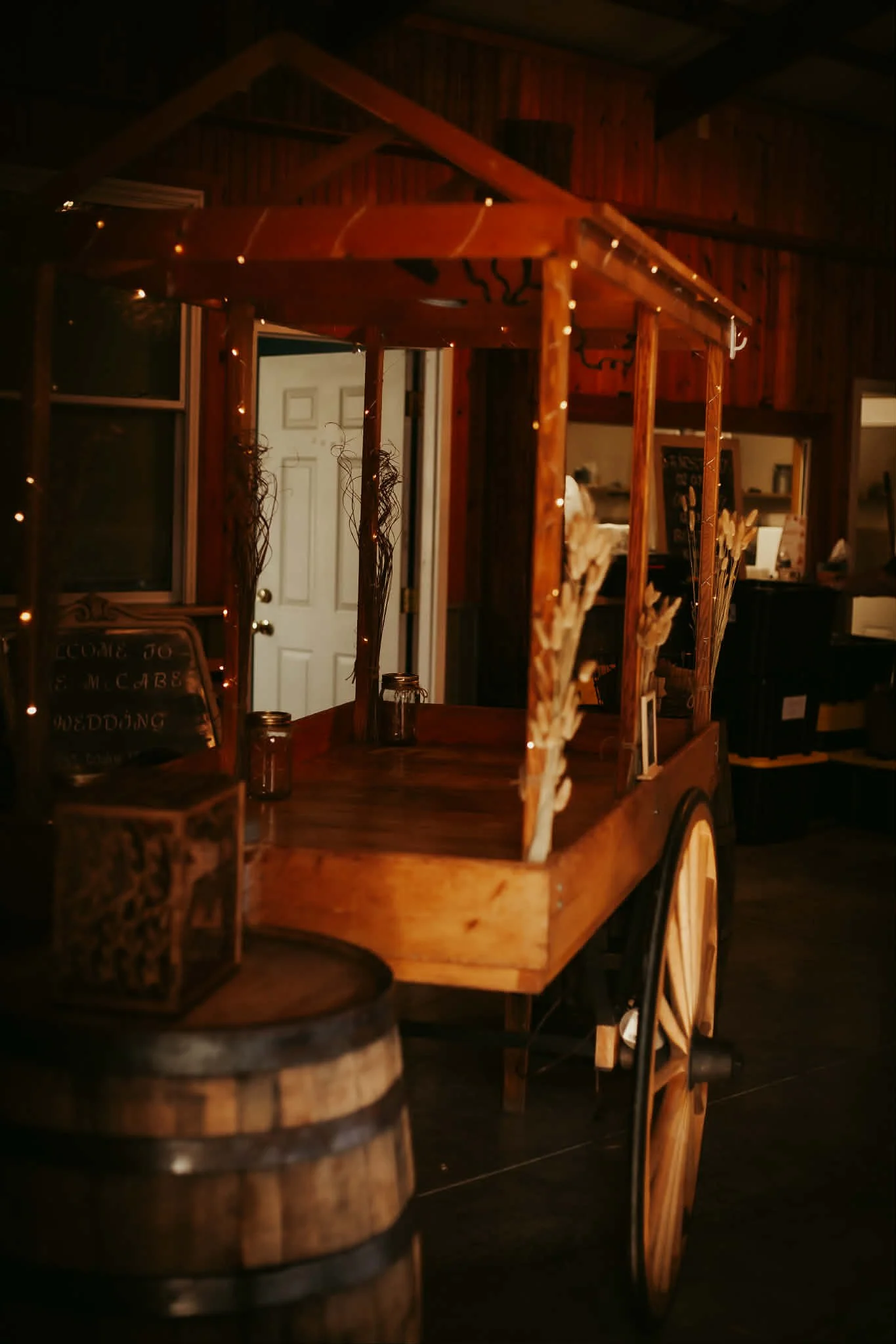 Rustic Lighted Wagon and Whiskey Barrel Display  Add charm and character to your wedding reception with our wagon complete with warm string lights and a classic whiskey barrel accent. This eye-catching piece creates the perfect rustic focal point and