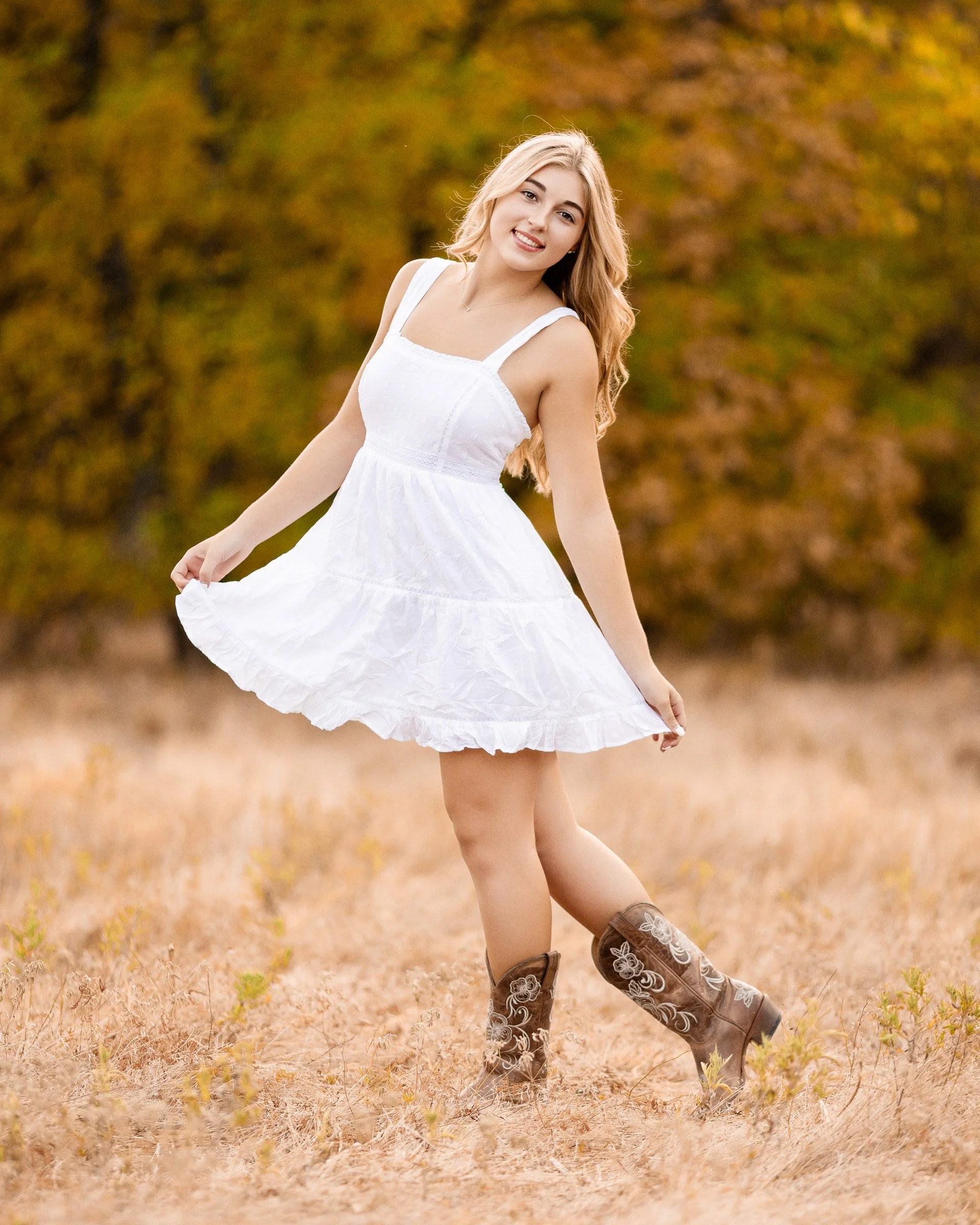 Dallas senior portrait photography girl wearing white dress and cowboy boots in fall field during high school senior session