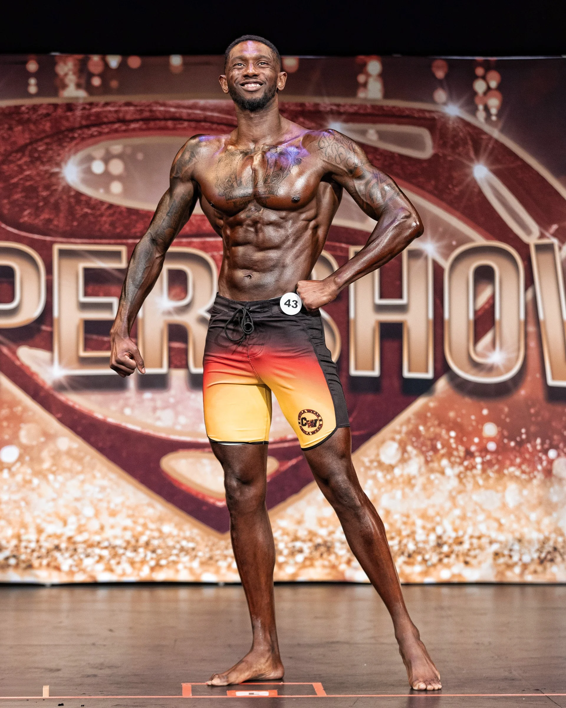 Natural Fit Federation bodybuilding competitor performing a powerful front pose during an individual routine on stage