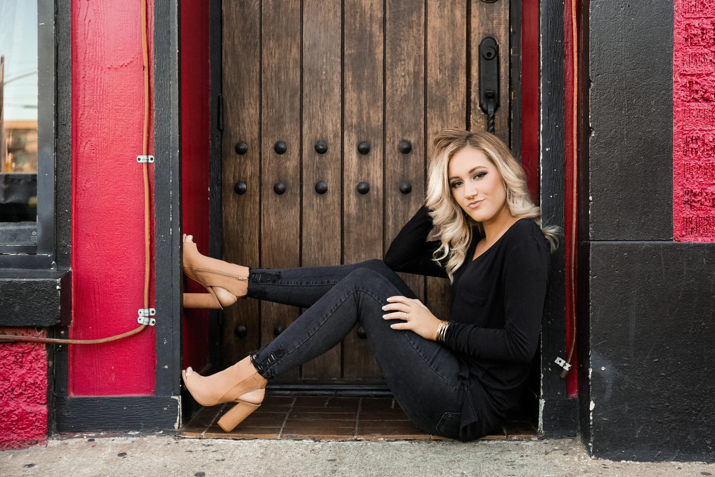 Confident Dallas high school senior portrait with modern skyline backdrop.