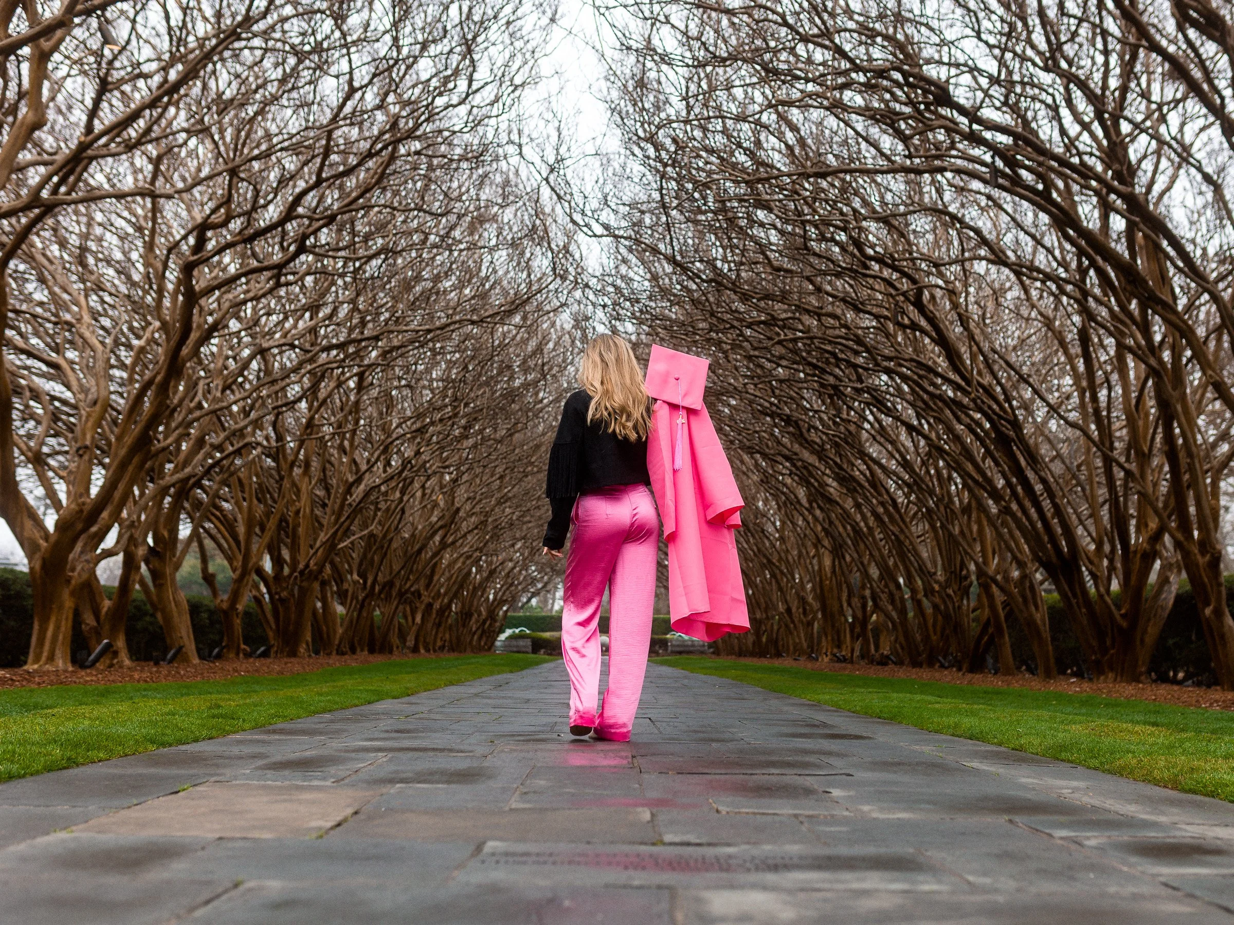 Senior portrait photography session in Dallas Texas graduate walking through tree tunnel during high school senior photo shoot by rgmphotography