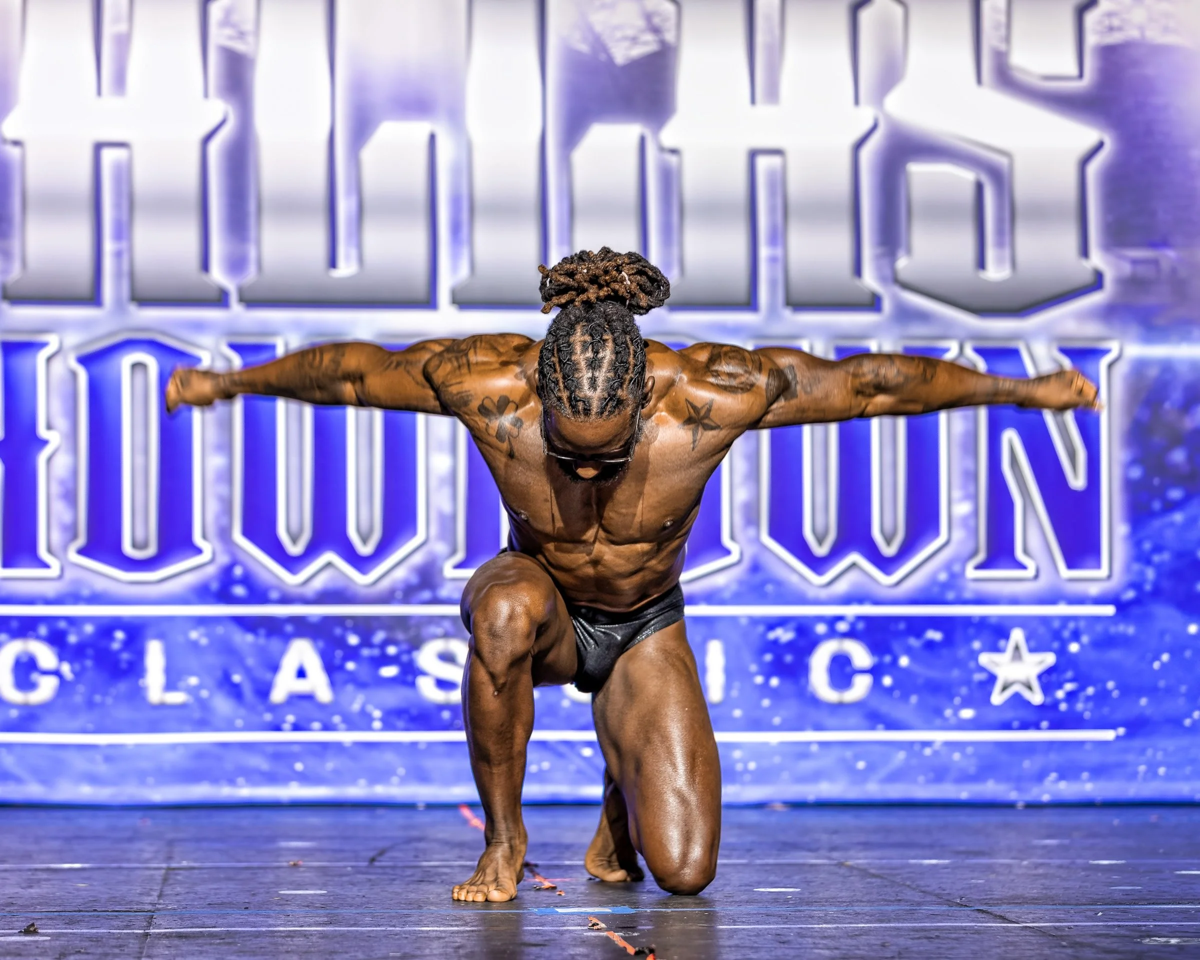 Natural Fit Federation physique competitor demonstrating confident stage presence during bodybuilding routine