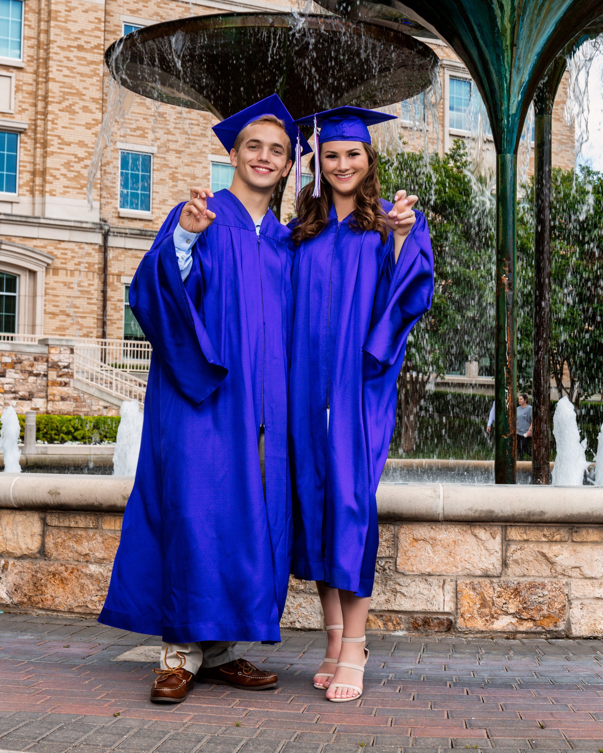 Dallas senior portrait photography college graduates wearing cap and gown at campus fountain