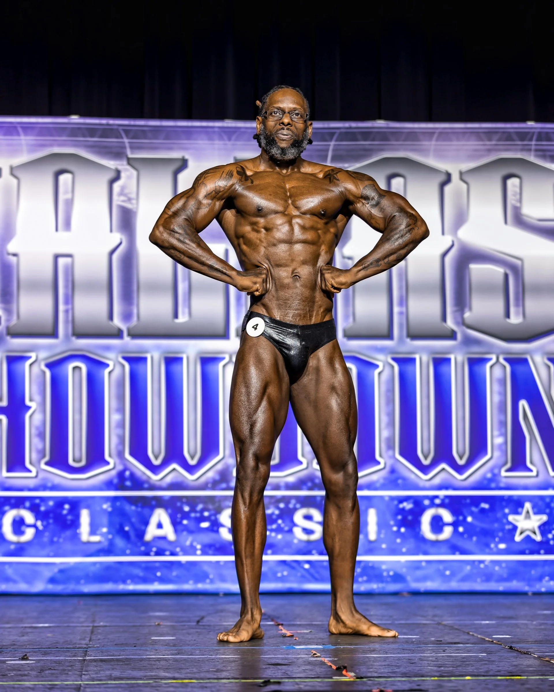 Natural Fit Federation physique competitor performing a stage pose during a bodybuilding competition routine