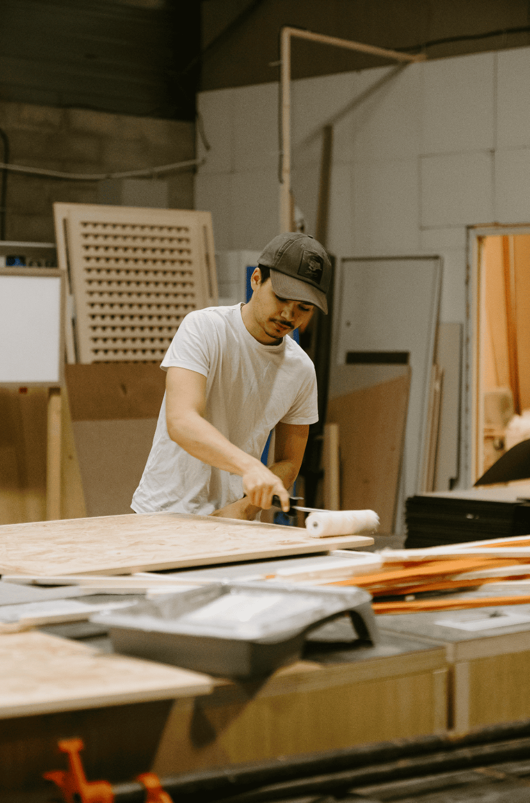 Reportage photo dans une menuiserie qui travaille le bois de récupération. Un homme travaille utilise un rouleau sur une pièce de bois large.