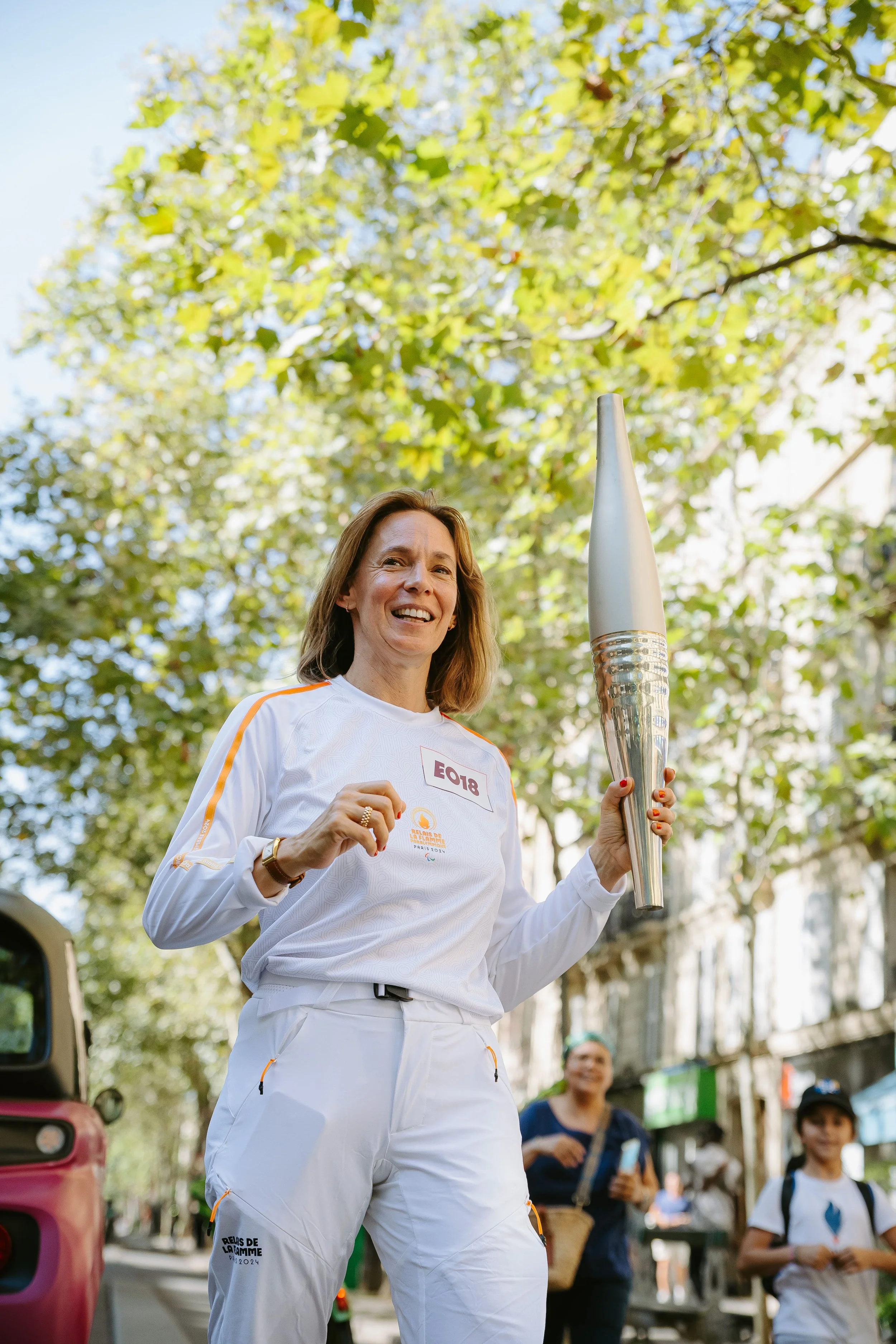 Elisa Yavchitz, souriante, porte la flamme Olympique, lors du passage de la flamme à Paris, à l'été 2024.