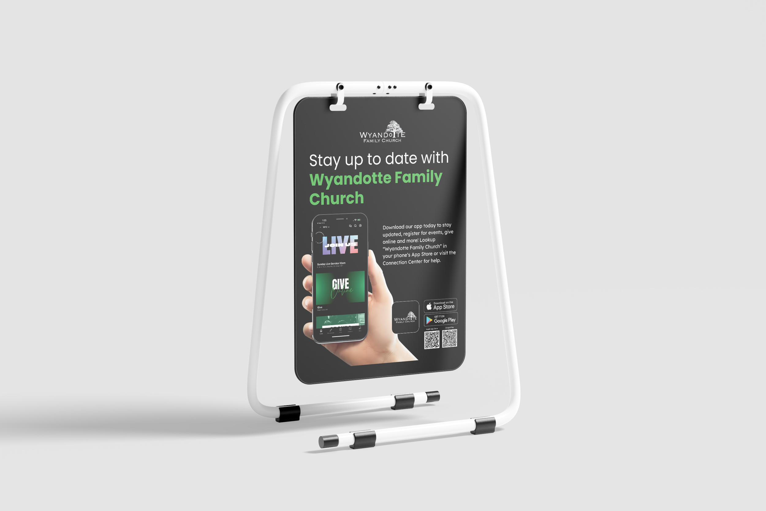 A white easel with a black sign promoting Wyandotte Family Church, featuring a smartphone displaying church app features, QR codes, and download options for app stores on a light grey background.