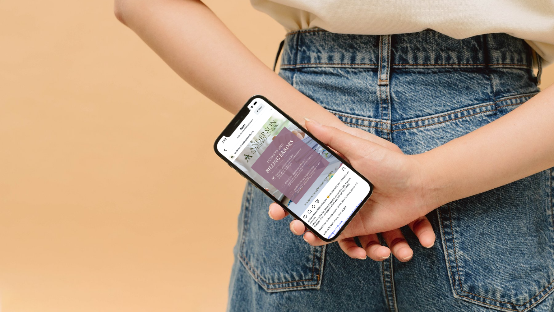 Person holding a smartphone displaying a website page about billing errors with a background of a beige wall and wearing blue denim jeans and a light-colored top.