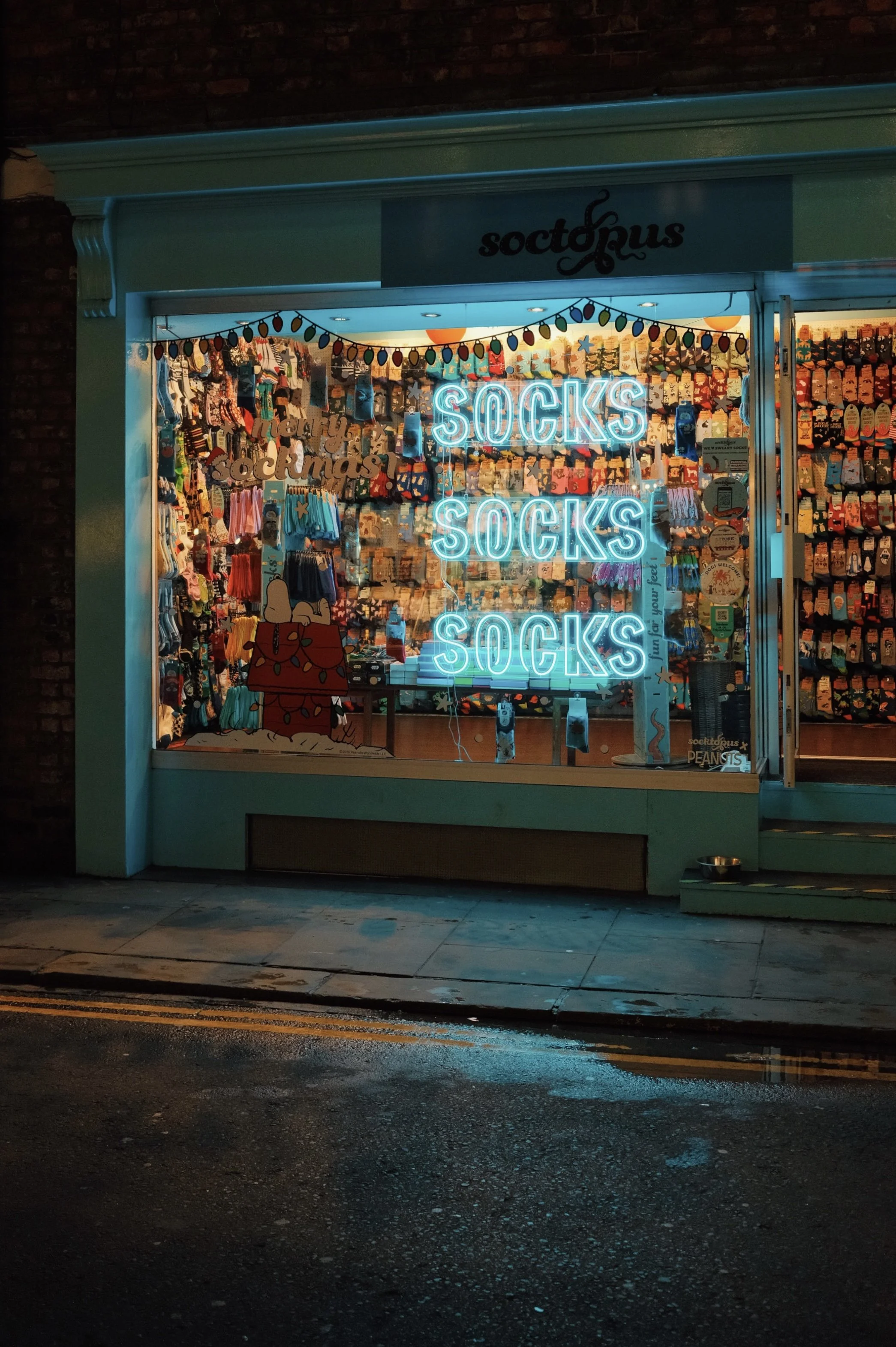 Storefront window advertising socks with neon sign reading 'SOCKS SOCKS SOCKS' and colorful sock displays inside.