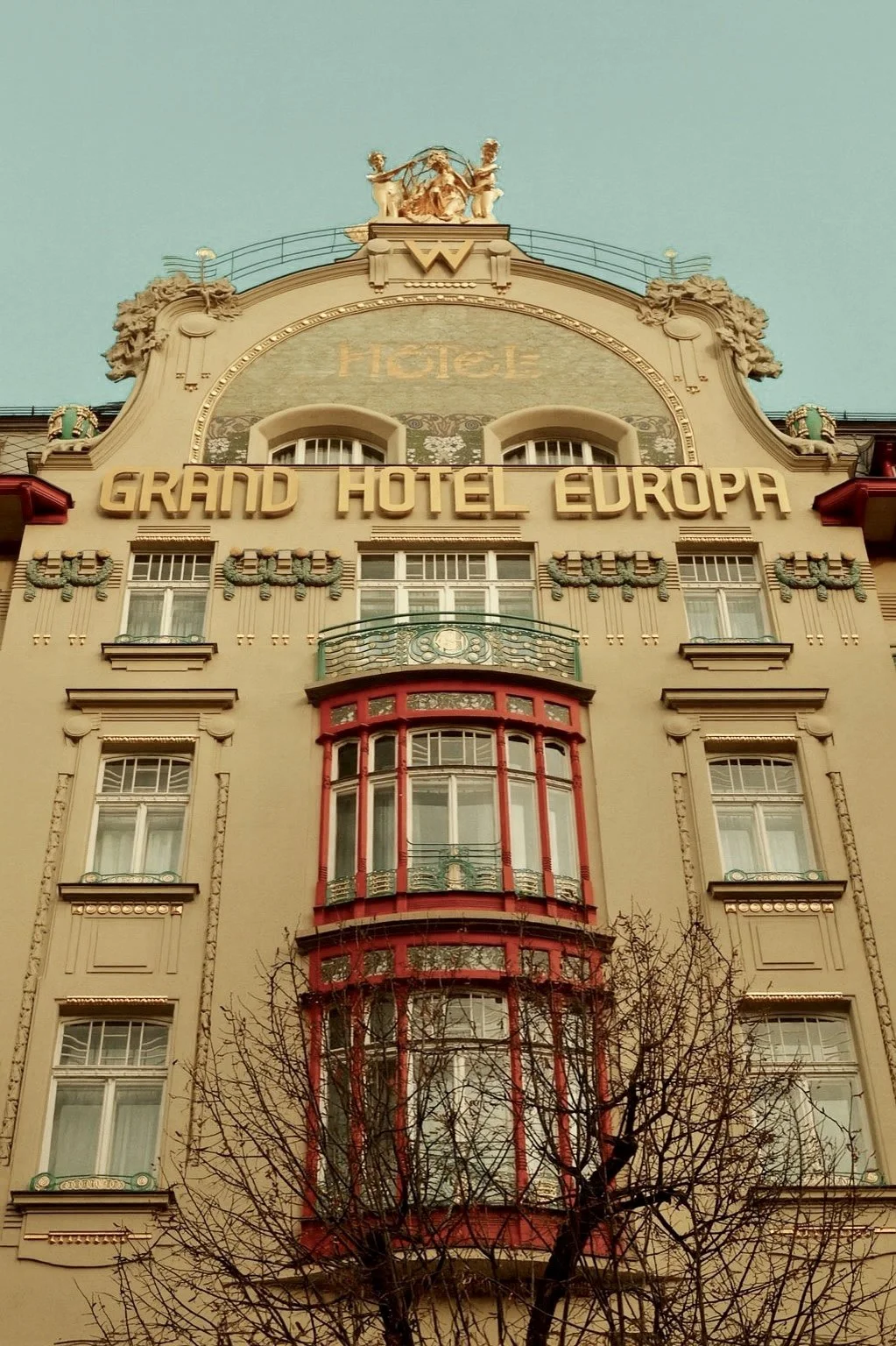 Facades of the Grand Hotel Europa with decorative architectural details and an ornate fixture at the top, under a clear sky.