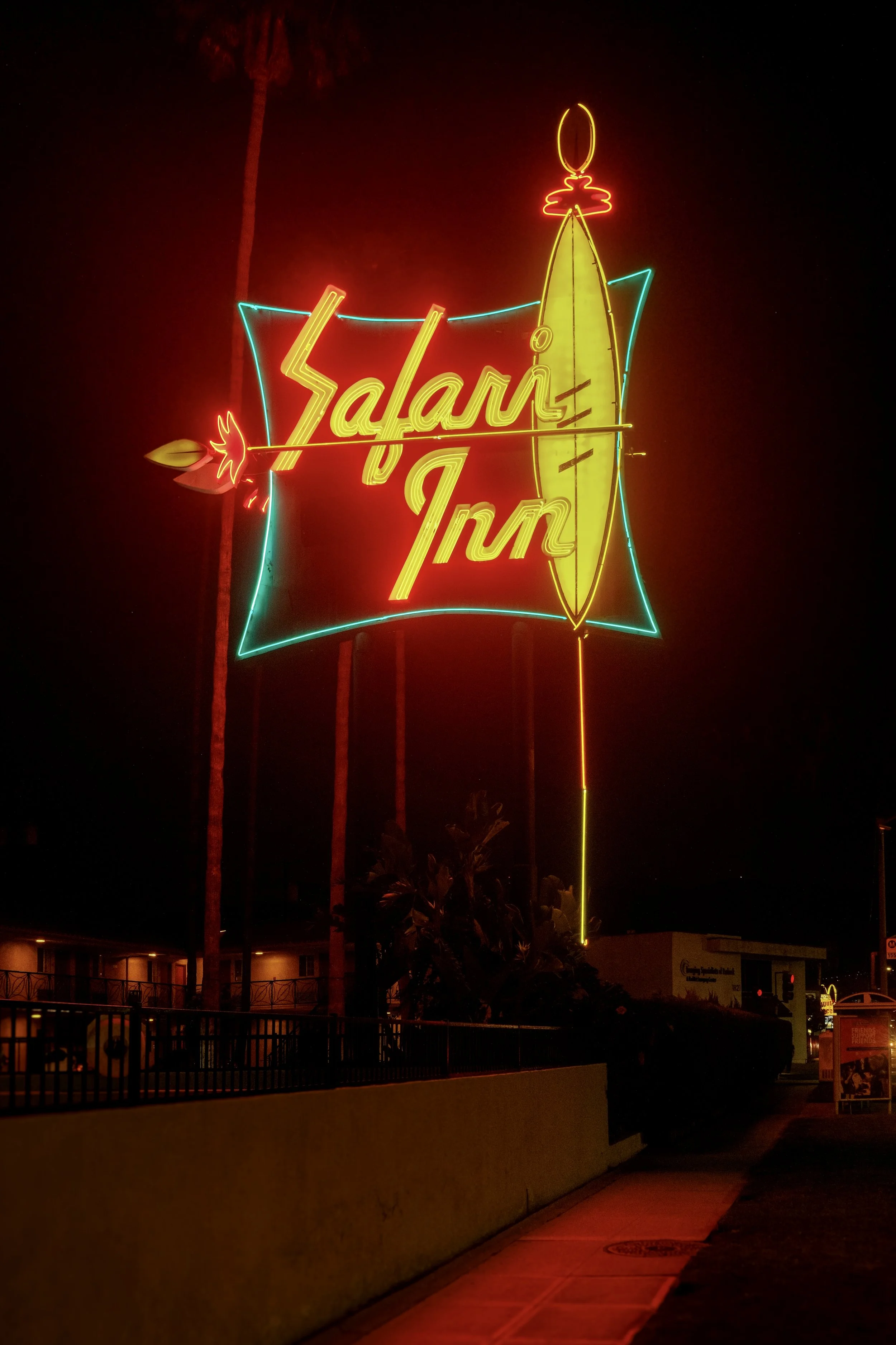 Neon sign displaying the words 'Salari Inn' with a surfboard and a palm tree, lit up at night.