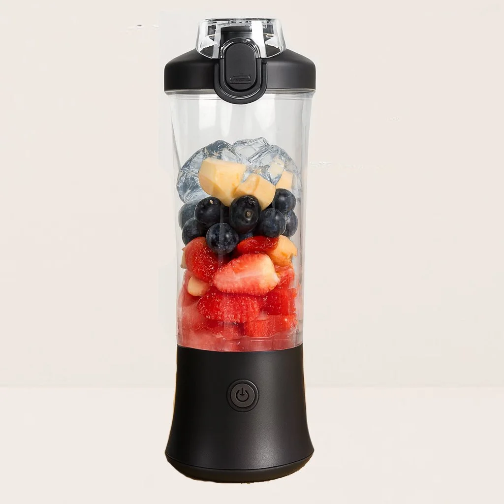 A portable blender filled with strawberries, blueberries, chunks of cheese, and ice cubes.