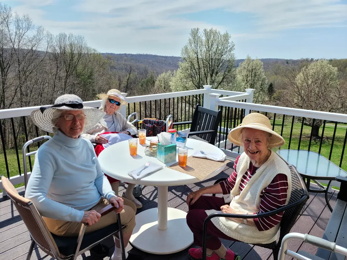 Residents enjoying a beautiful day on the deck with their friends. They are smiling and enjoying the companionship with their friends.