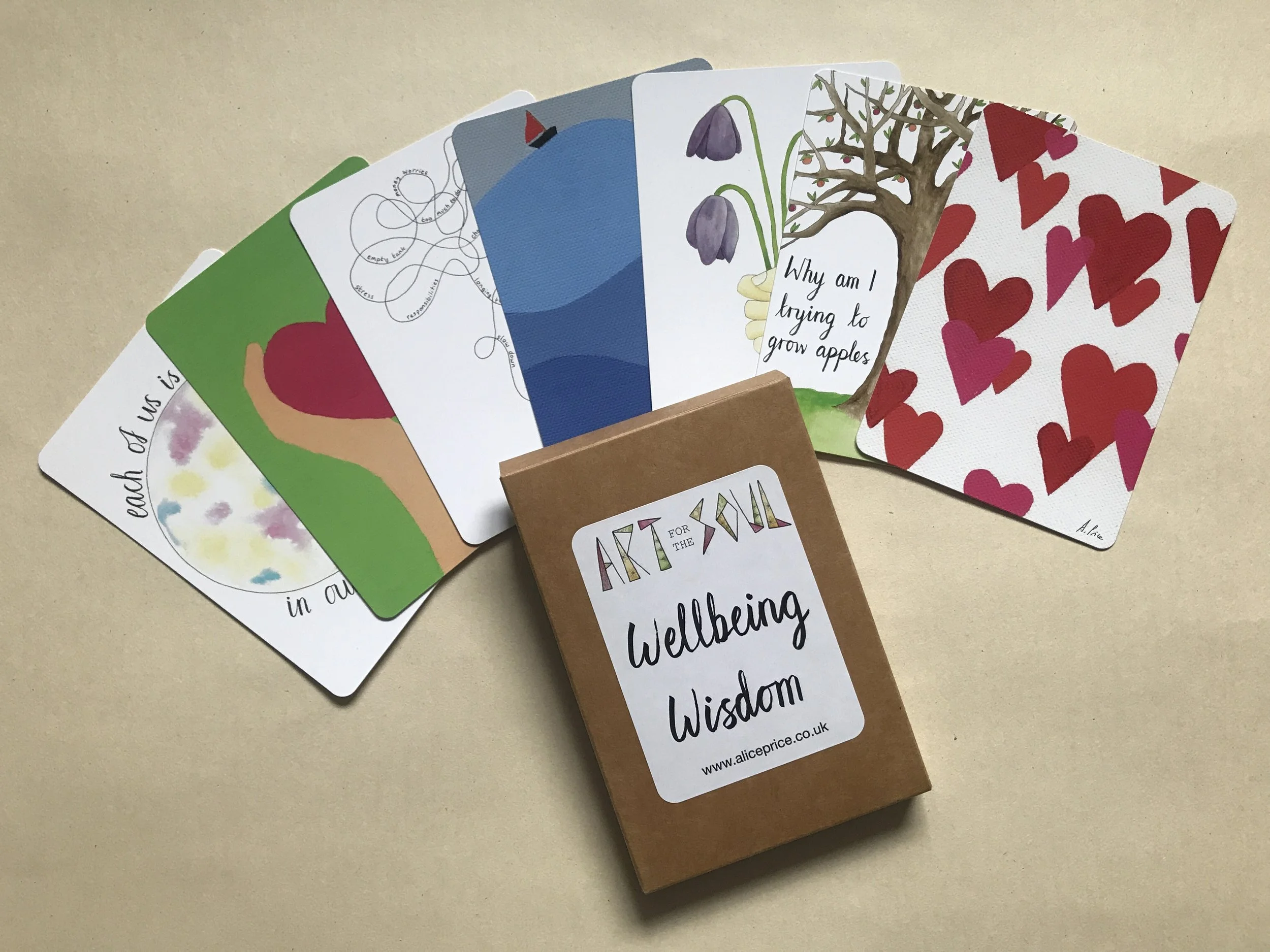 7 art postcards in a fan layout with a brown cardboard box and the label 'Art for the Soul, Wellbeing Wisdom'