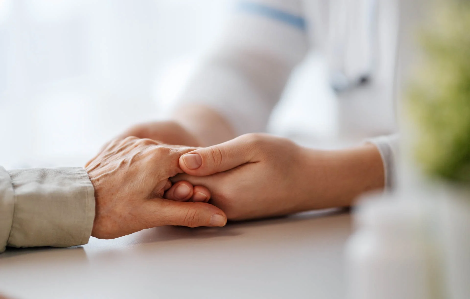 A caregiver holding an elderly person's hand, showing compassion and support.