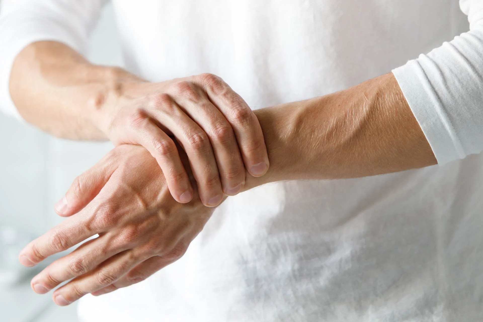 A person holding their wrist with their other hand, demonstrating wrist pain or injury.