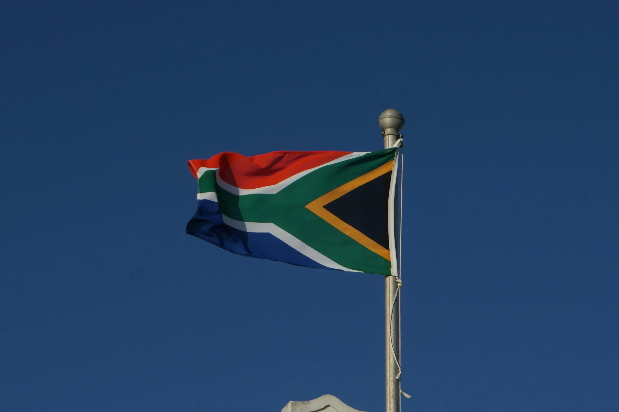 South African flag flying against clear blue sky.