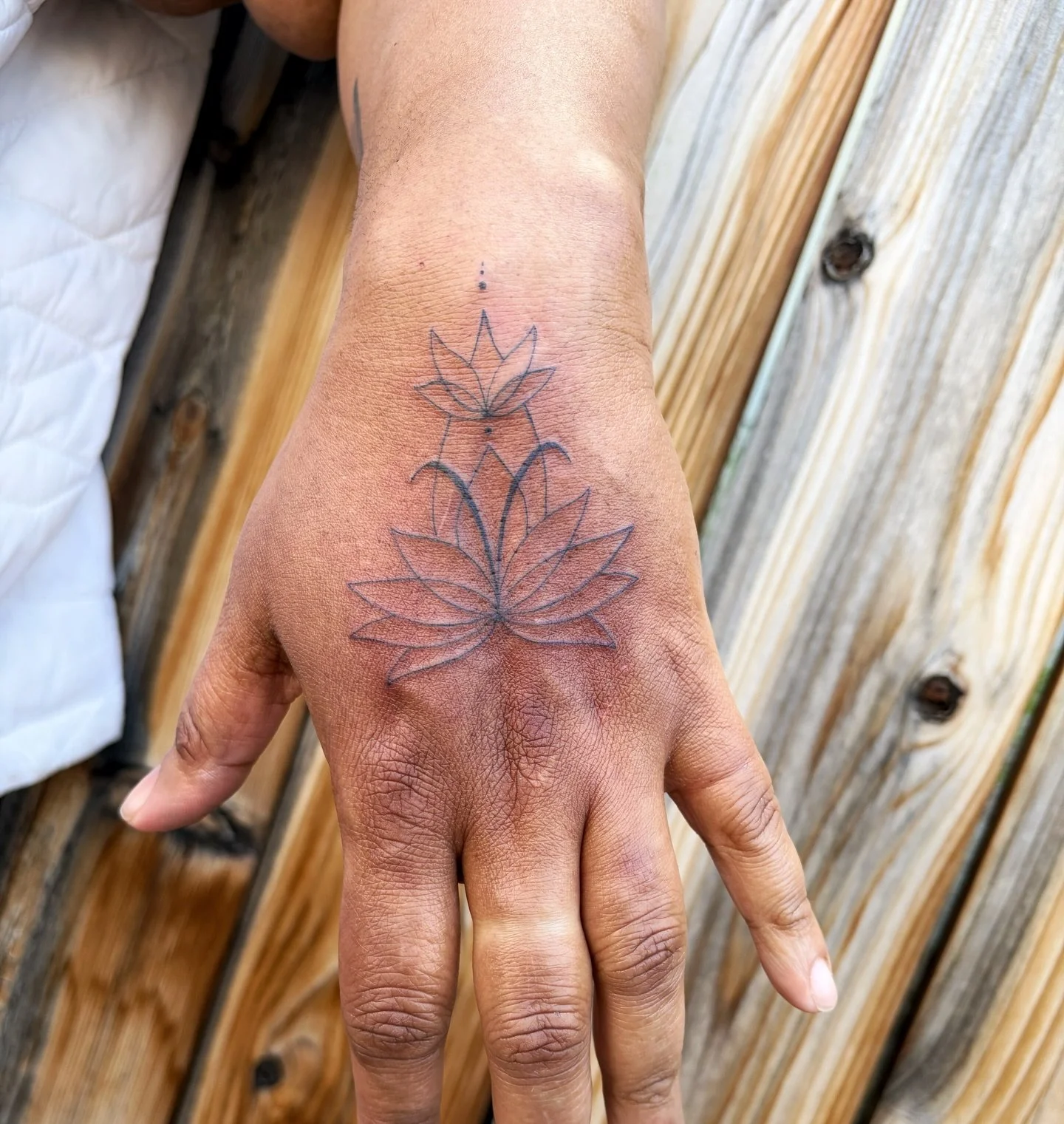 Dainty hand lotus by @goatwitchtattoo