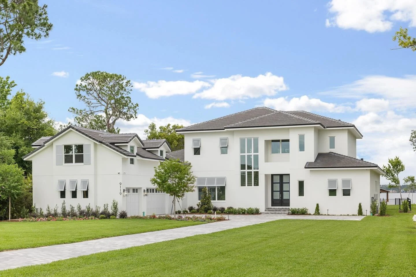 long drive way to perfectly maintained landscaping and white home. 