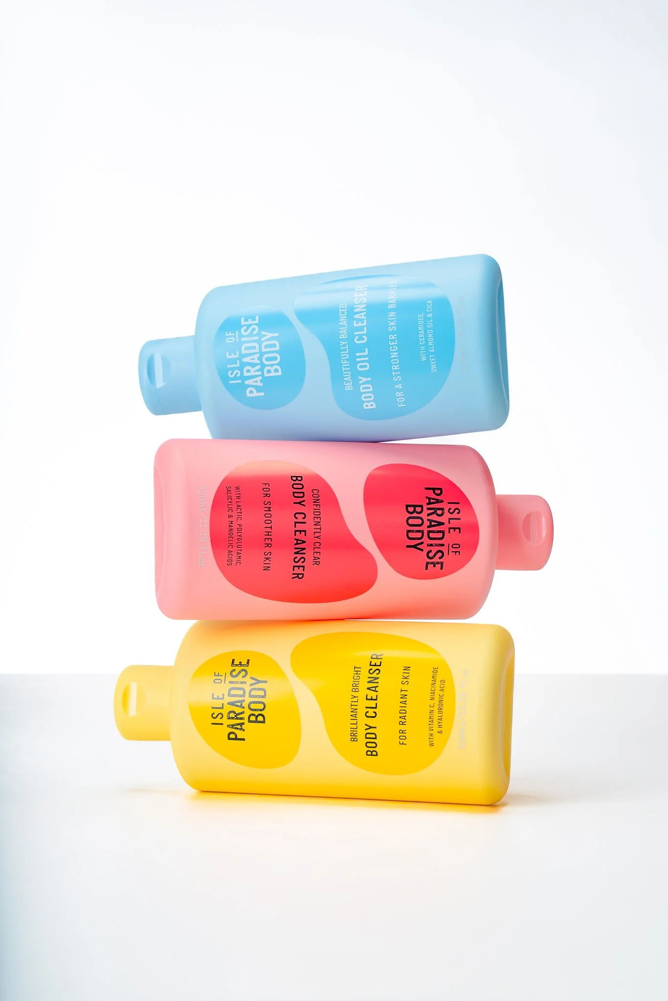 Three colorful bottles of Isle of Paradise body care products stacked on a white surface.