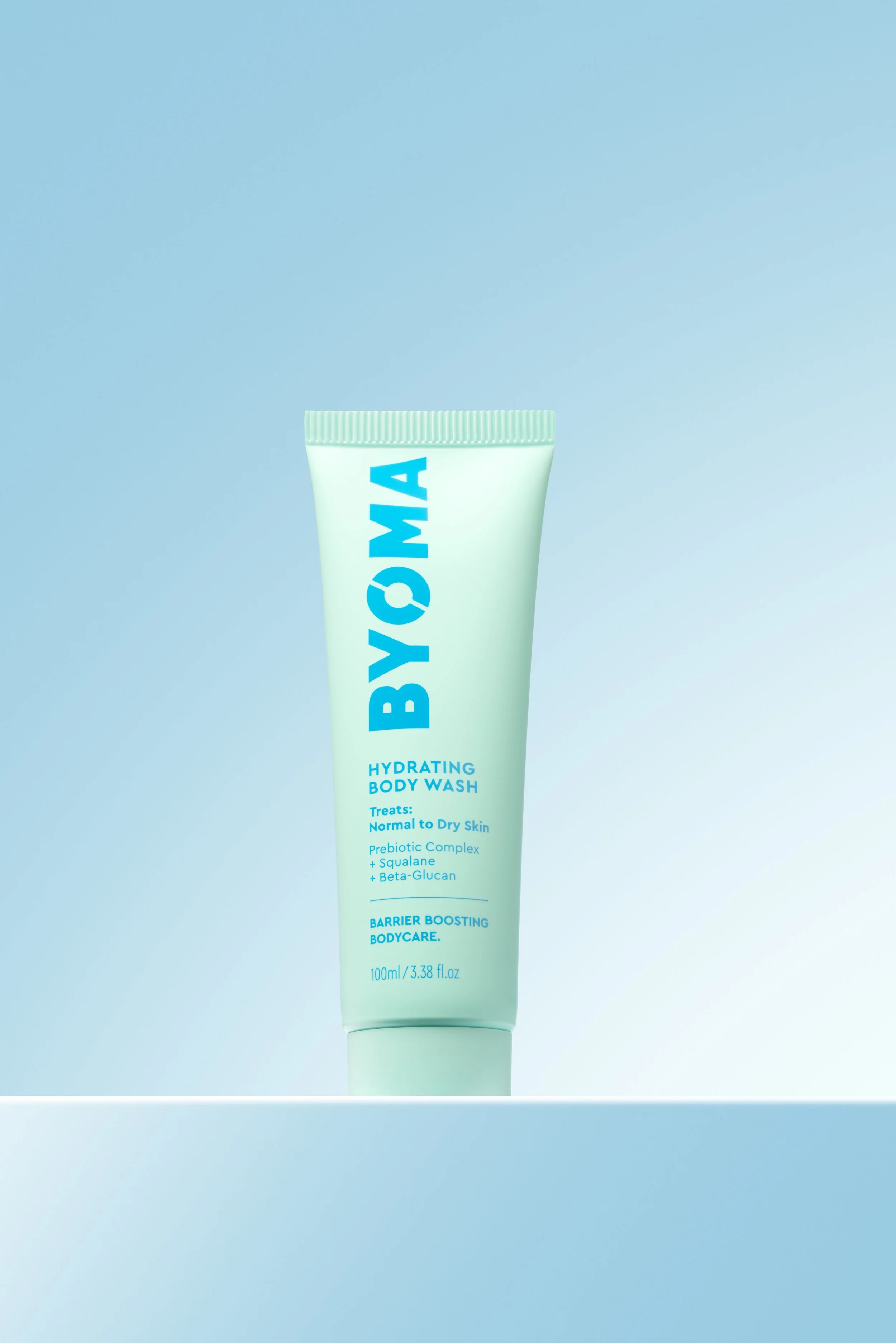 A tube of BYOMA Hydrating Body Wash standing on a white surface with a light blue background.