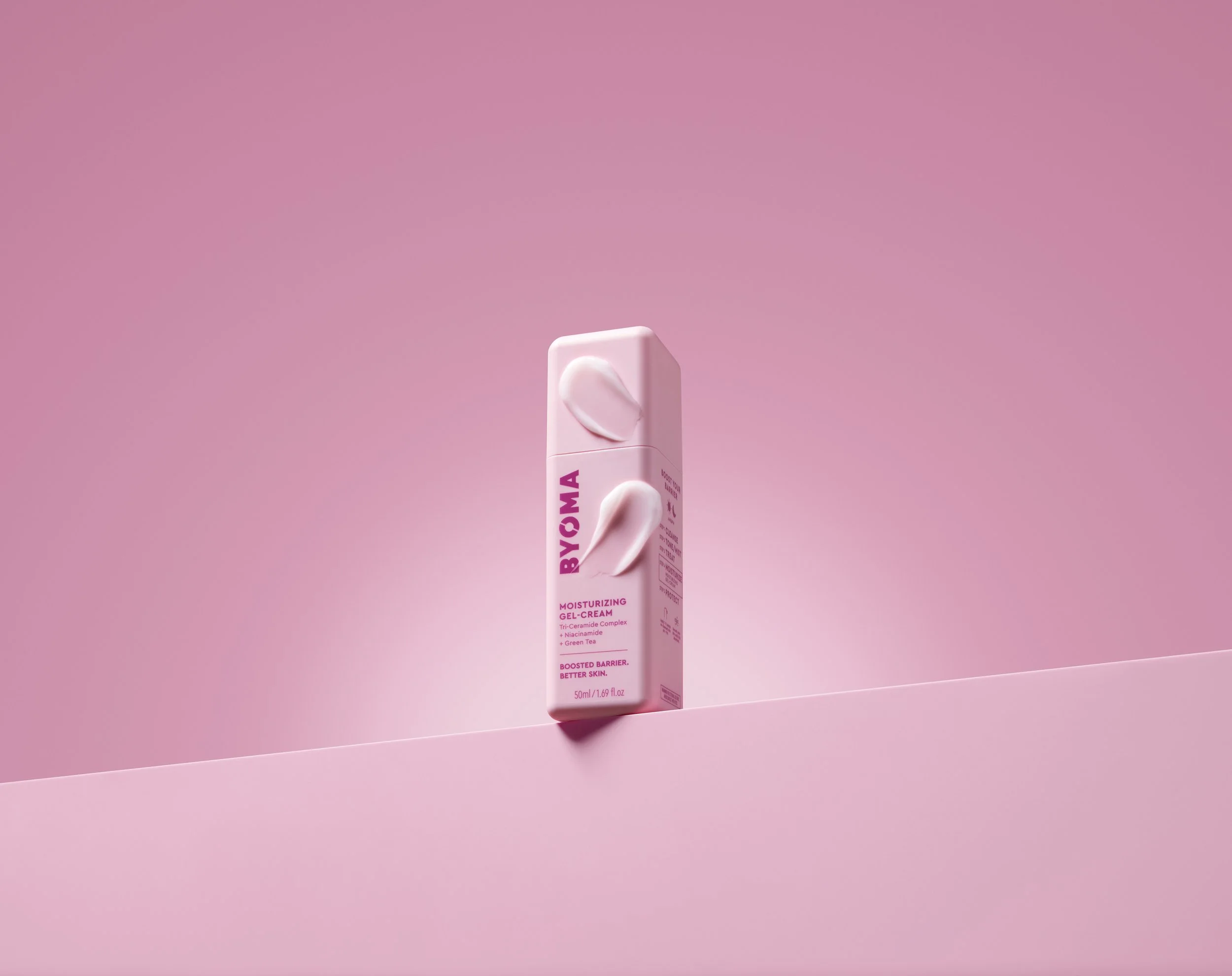 A pink box of BYOMA moisturizing gel cream with a white cream dollop on the packaging, placed on a pink surface with a pink background.