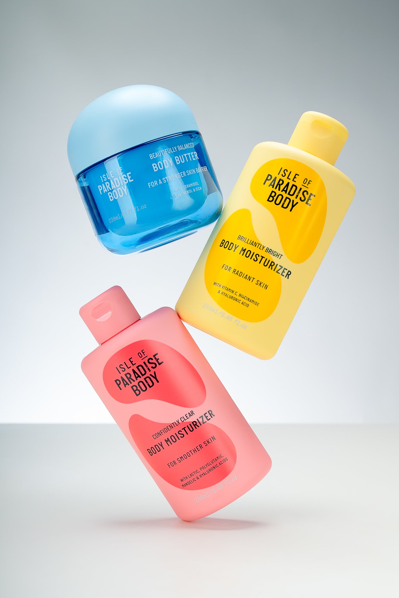 Three Isle of Paradise body care products floating against a neutral background.